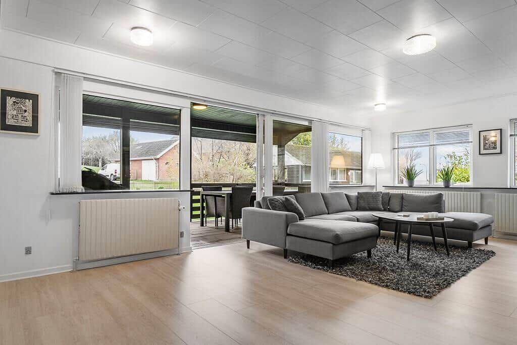 Wohnzimmer mit grauem Sofa, Holzboden und Blick auf Terrasse.
