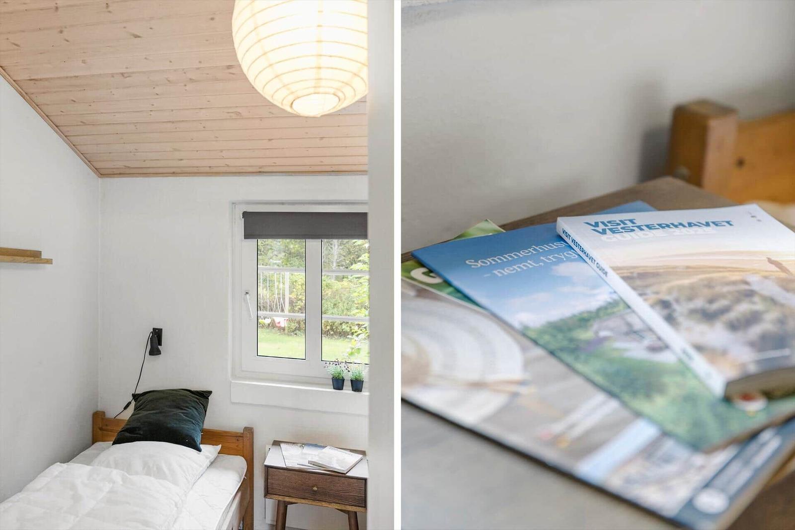 Schlafzimmer mit Bett, Fenster und Lampe. Tisch mit Reiseführern.