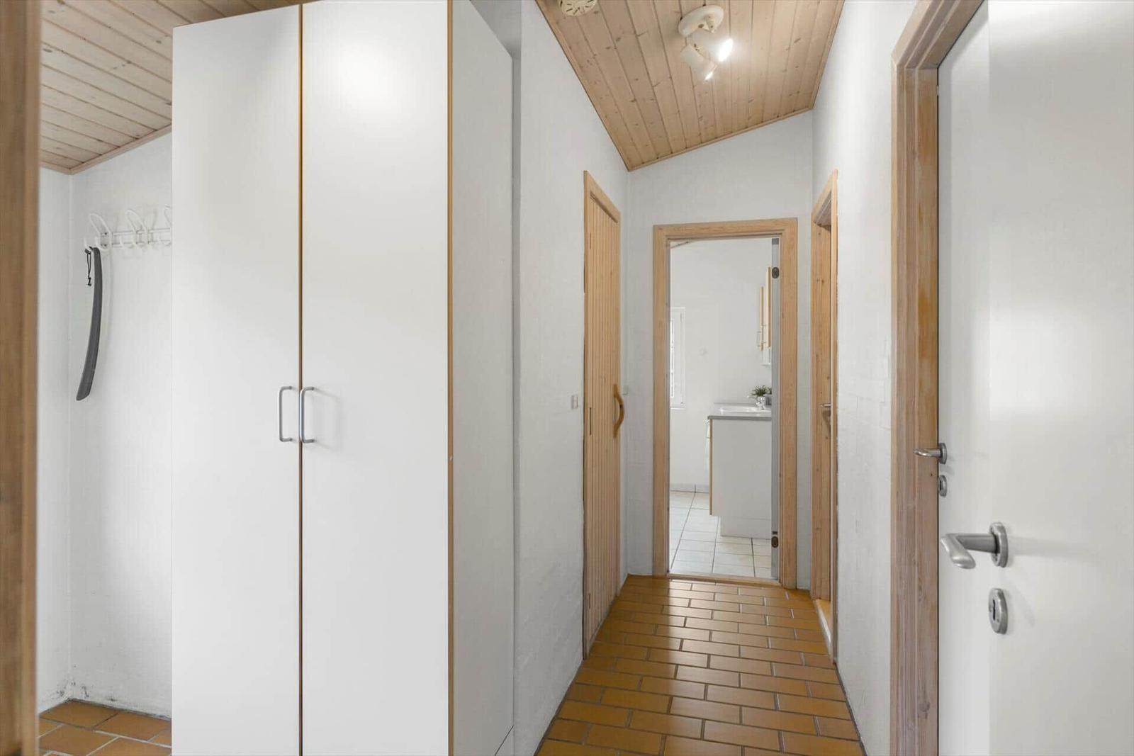 Flur mit Kleiderschrank, Holzdecke und Blick in die Küche.