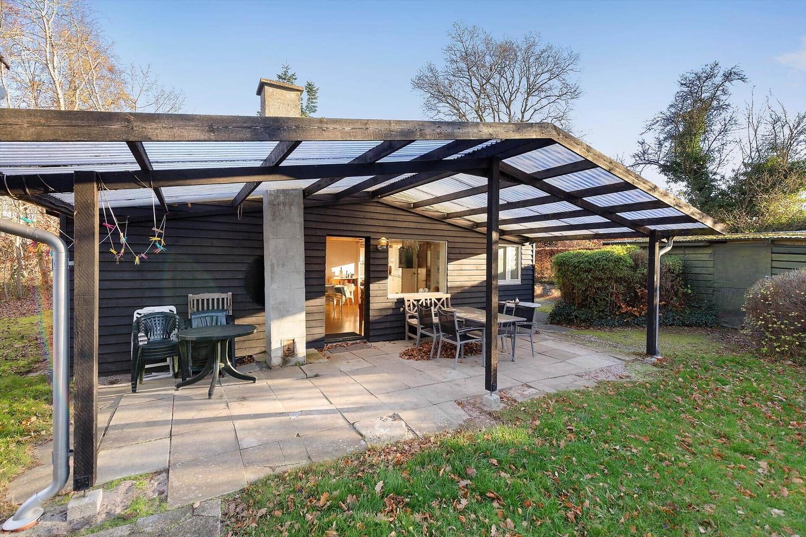 Terrace with table and chairs under roof, view into living area.