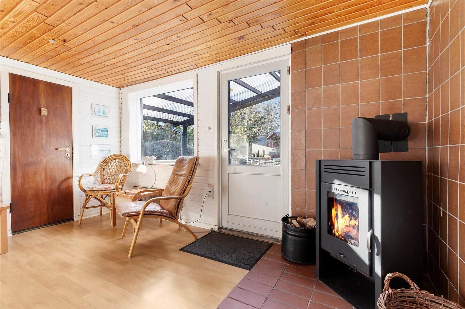 Room with wooden ceiling, fireplace, and two chairs. Entrance to terrace.