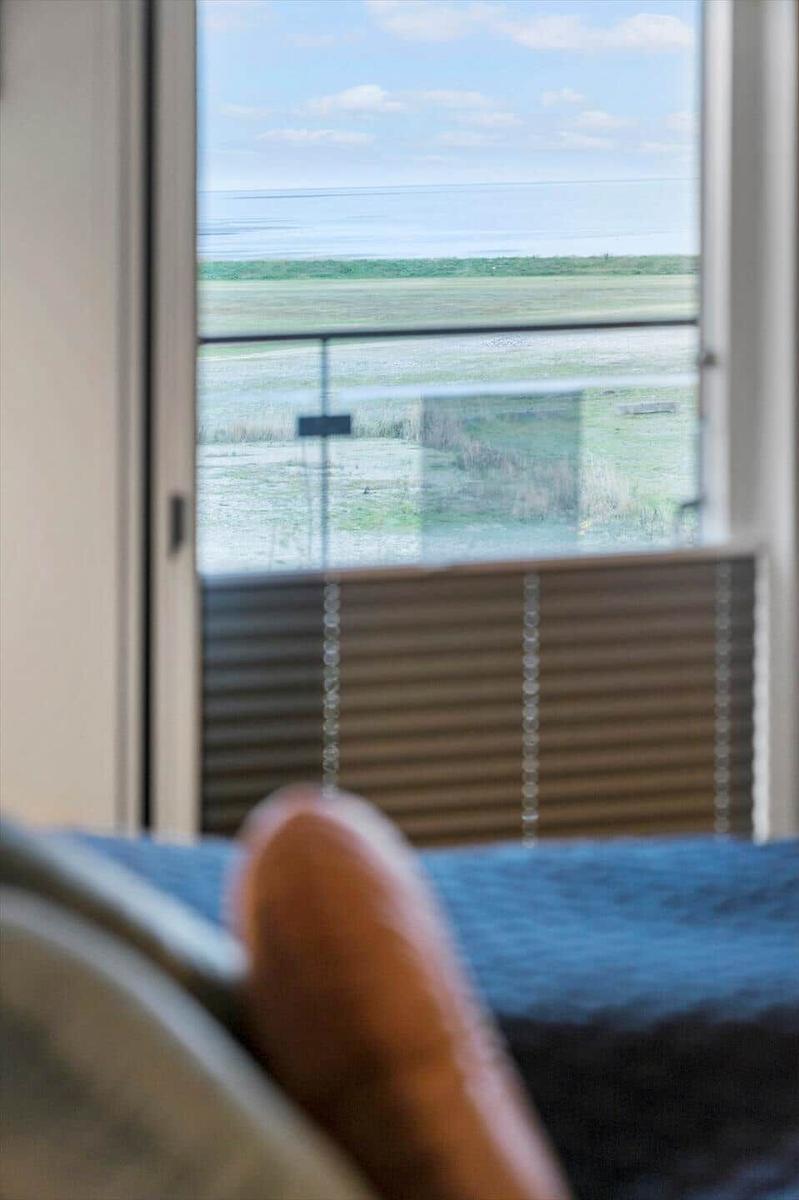 Aus dem Fenster blickt man auf eine grüne Landschaft und das Meer.