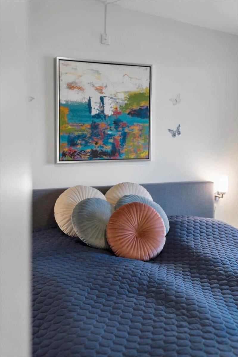 Ein Bett mit runden Kissen und einem abstrakten Bild an der Wand.