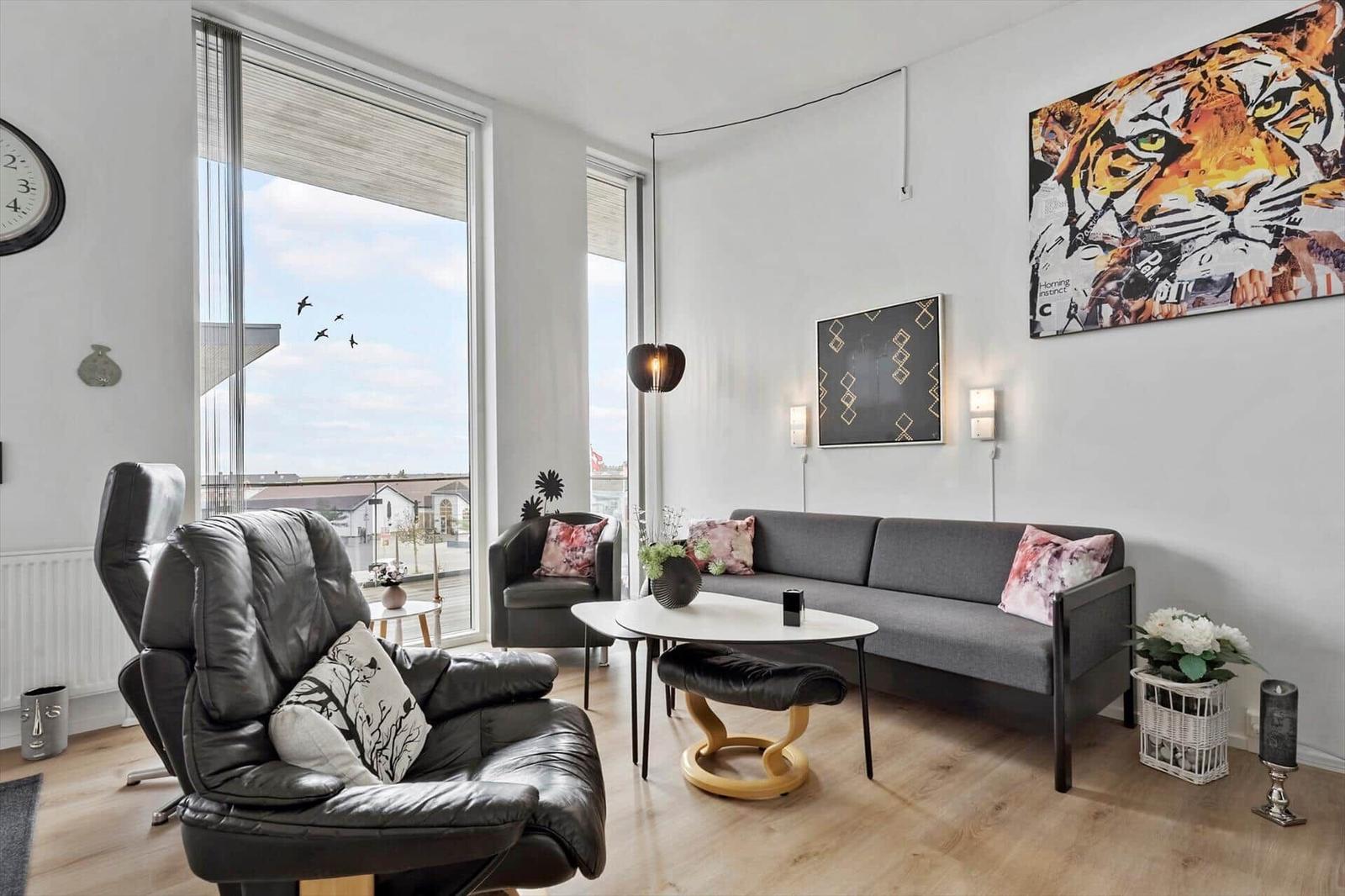 Wohnzimmer mit Sofa, Sessel und großem Fenster mit Blick.