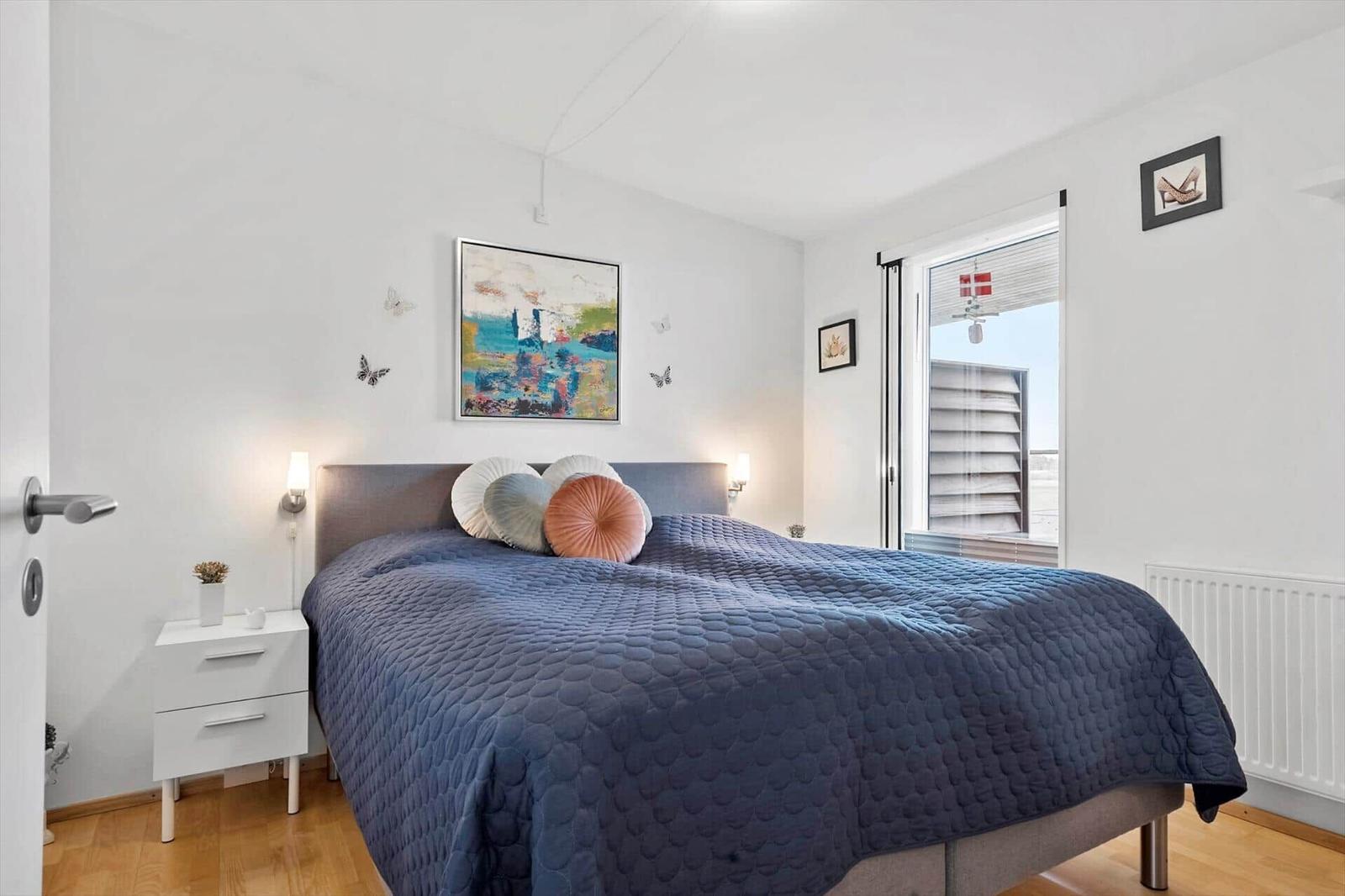 Schlafzimmer mit Bett, Nachttisch und Fenster.