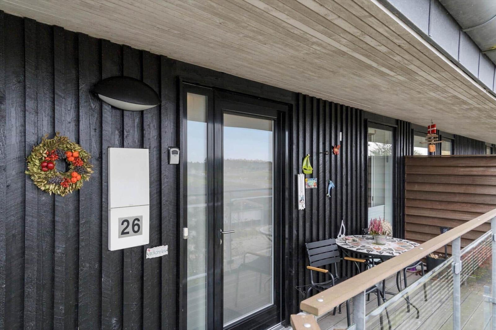 Eingang mit Tür und kleinem Balkon mit Tisch und Stühlen.
