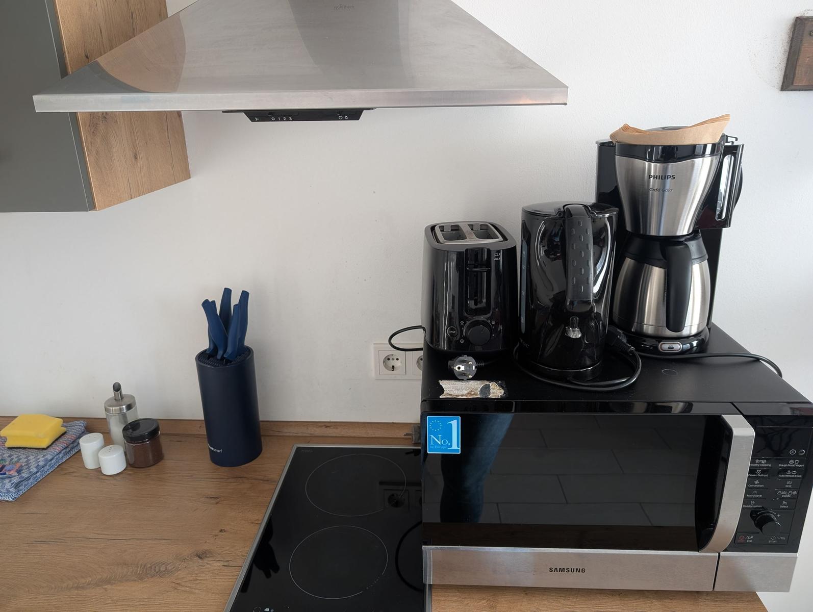Küche mit Herd, Mikrowelle und Kaffeemaschine.