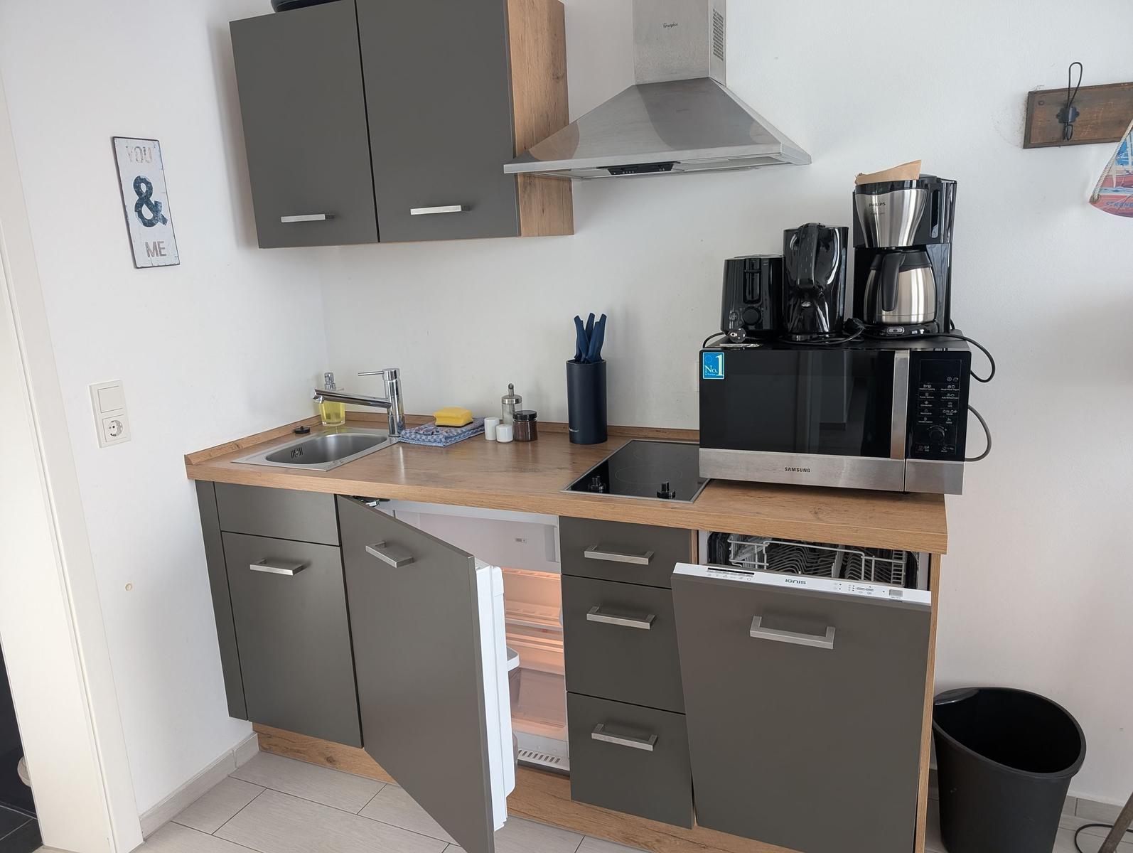 Küche mit Spüle, Herd, Kühlschrank und Mikrowelle.