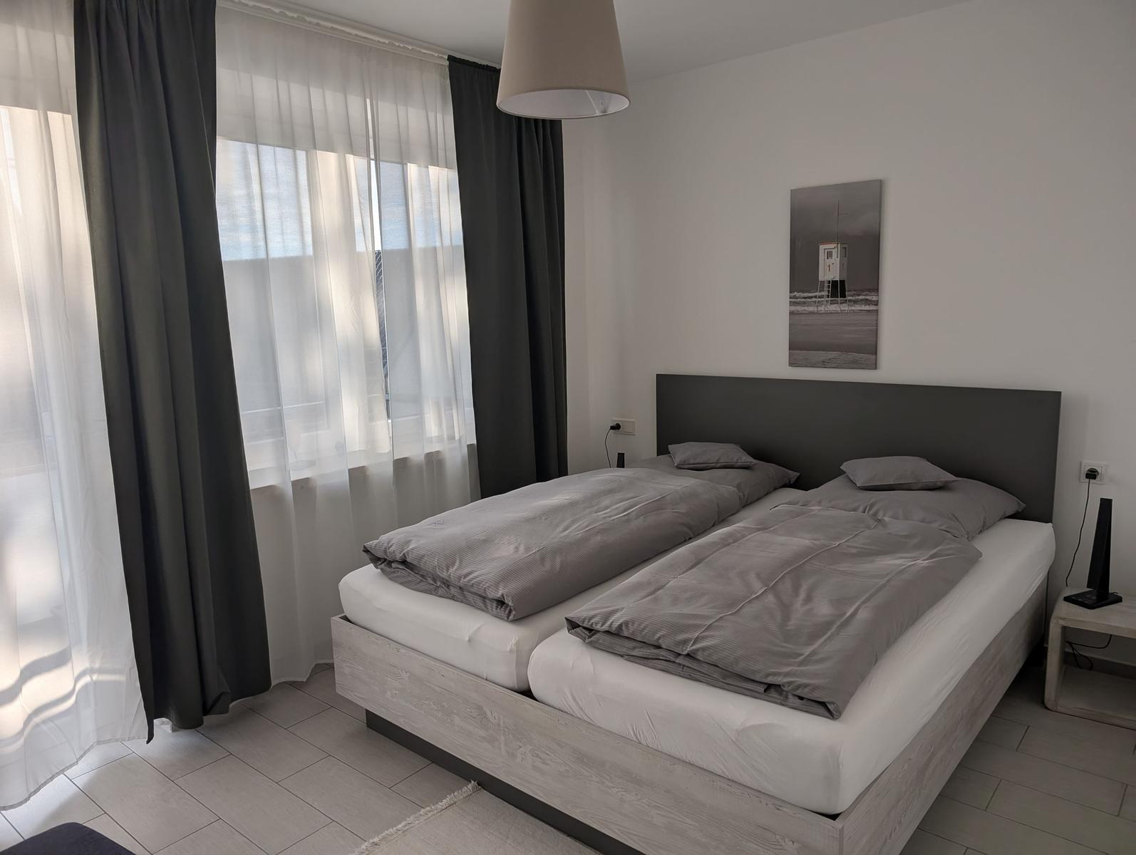 Schlafzimmer mit Doppelbett, Fenster und Wandbild.