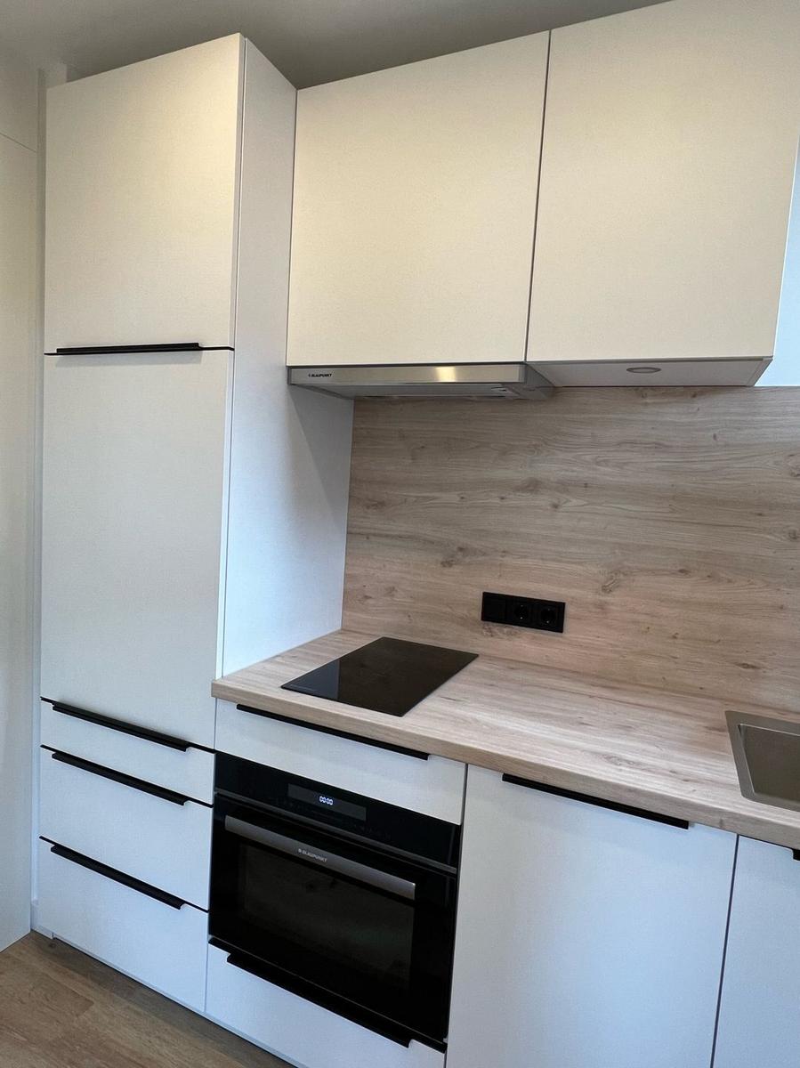 Moderne Küche mit weißen Schränken, Holz Arbeitsplatte und eingebauter Kochplatte.