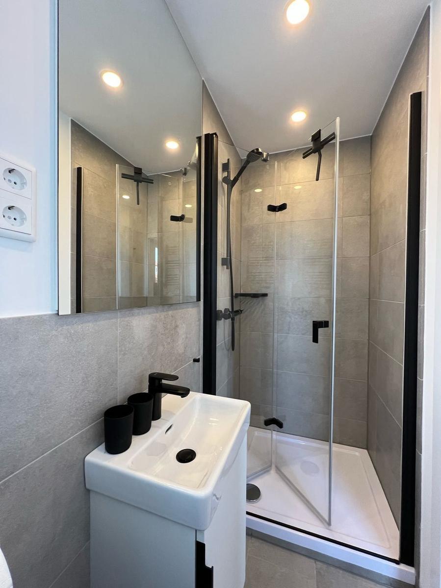 Badezimmer mit Dusche, Waschbecken und Spiegel.