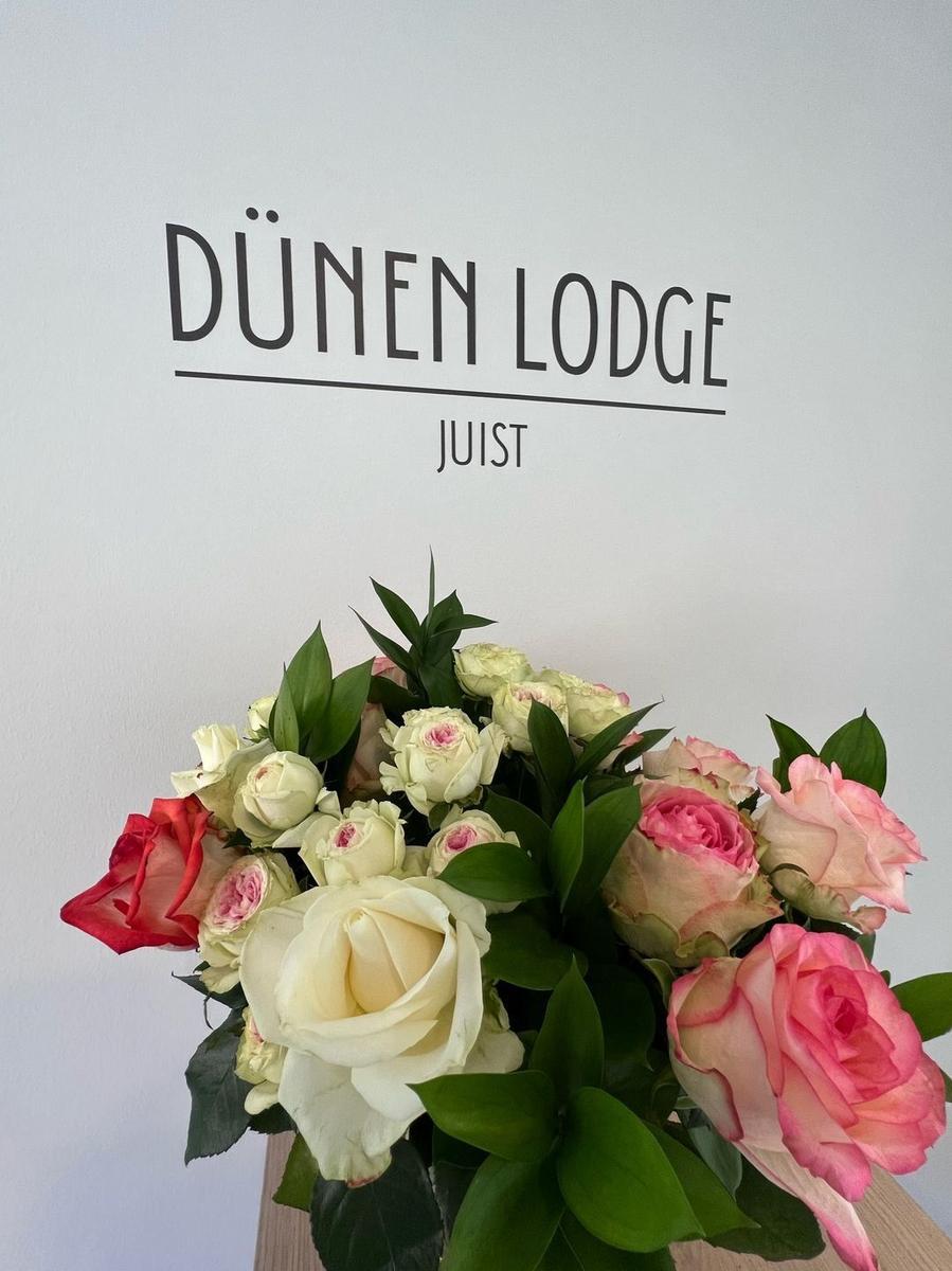 Bouquet mit Rosen vor Wand mit Schriftzug DÜNEN LODGE JUIST