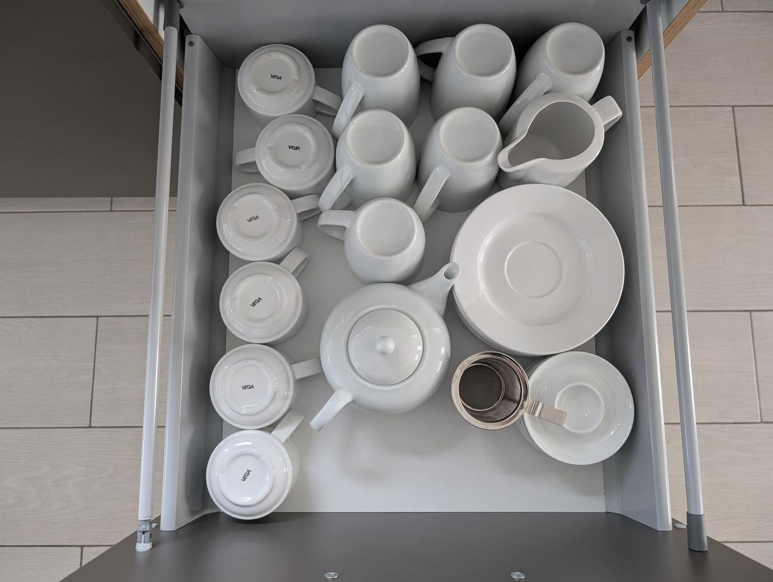 Küchenschrank mit weißer Porzellan-Kaffeekanne und Tassen