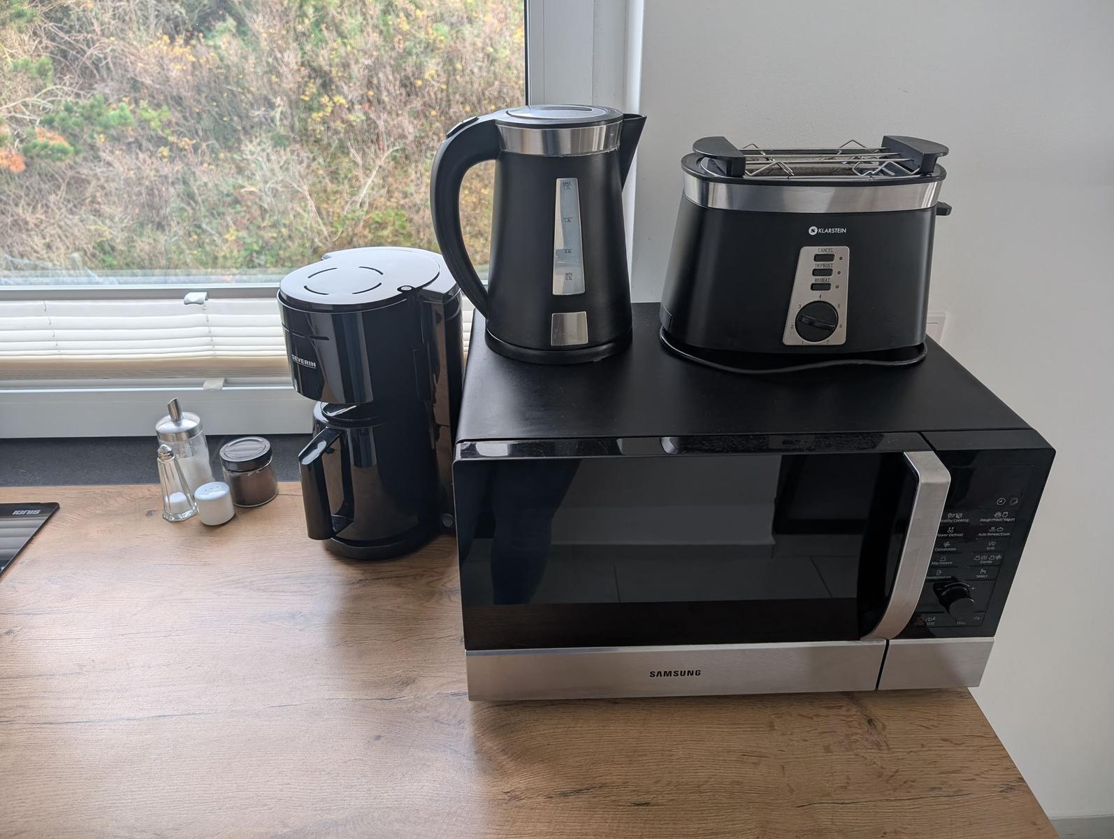 Küchenzeile mit Mikrowelle, Kaffeemaschine, Wasserkocher und Toaster.