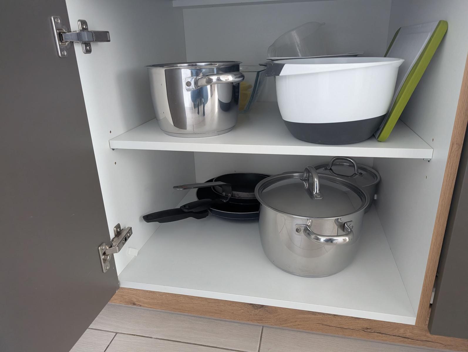 Küchenschrank mit Pfannen und Topfen. Aufbewahrungsort für Küchenutensilien.