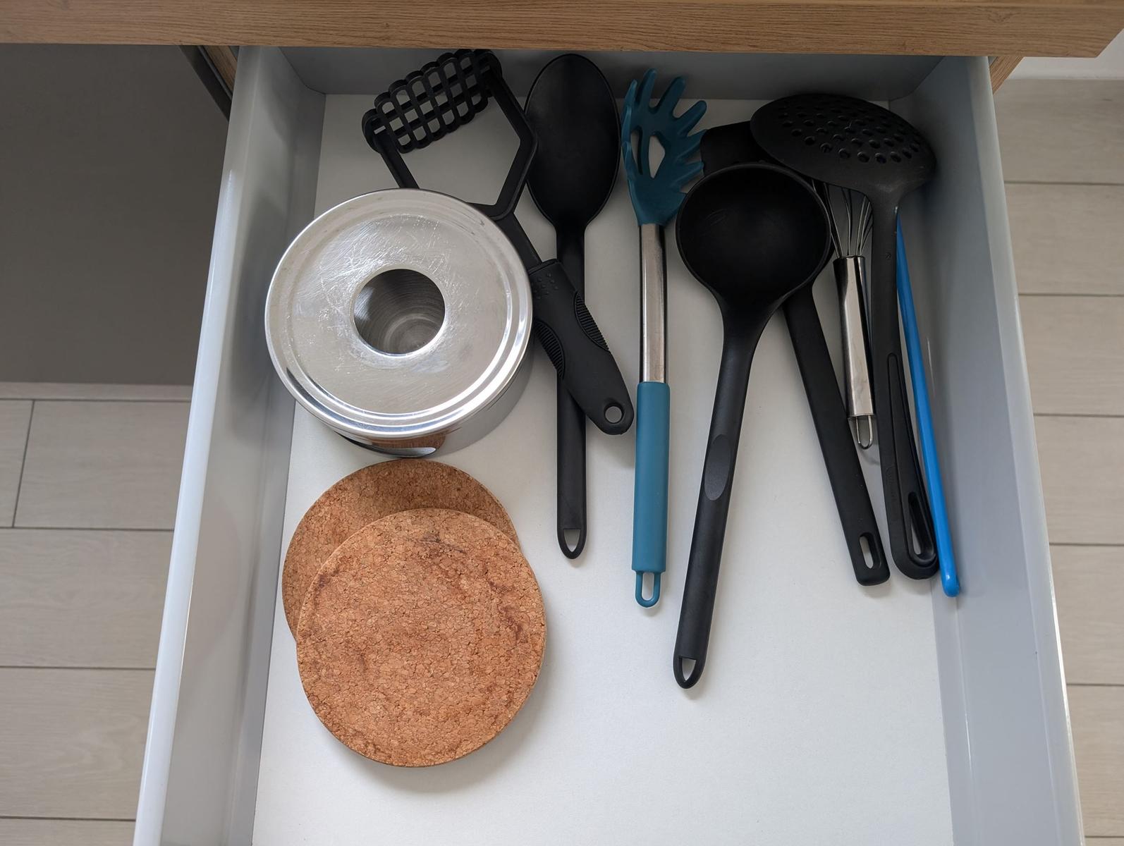 Küchenkasten mit Kochutensilien und Korkuntersetzern