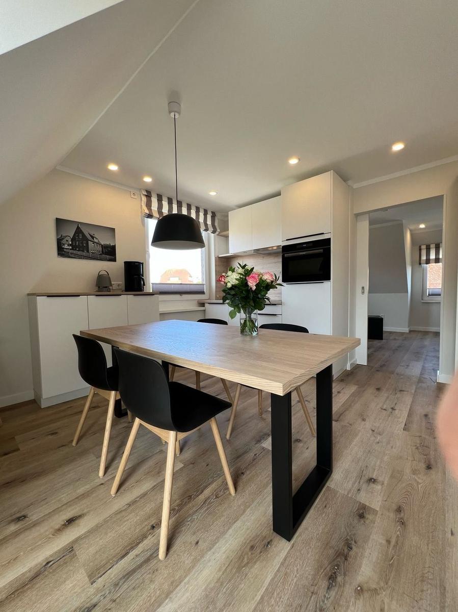 Essbereich mit Tisch, Stühlen und Küchenzeile unter schrägem Dach.