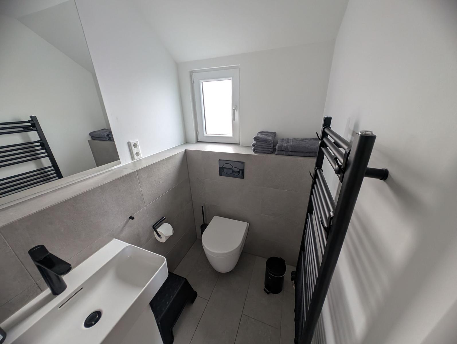 Badezimmer mit Toilette, Waschbecken und Heizkörper