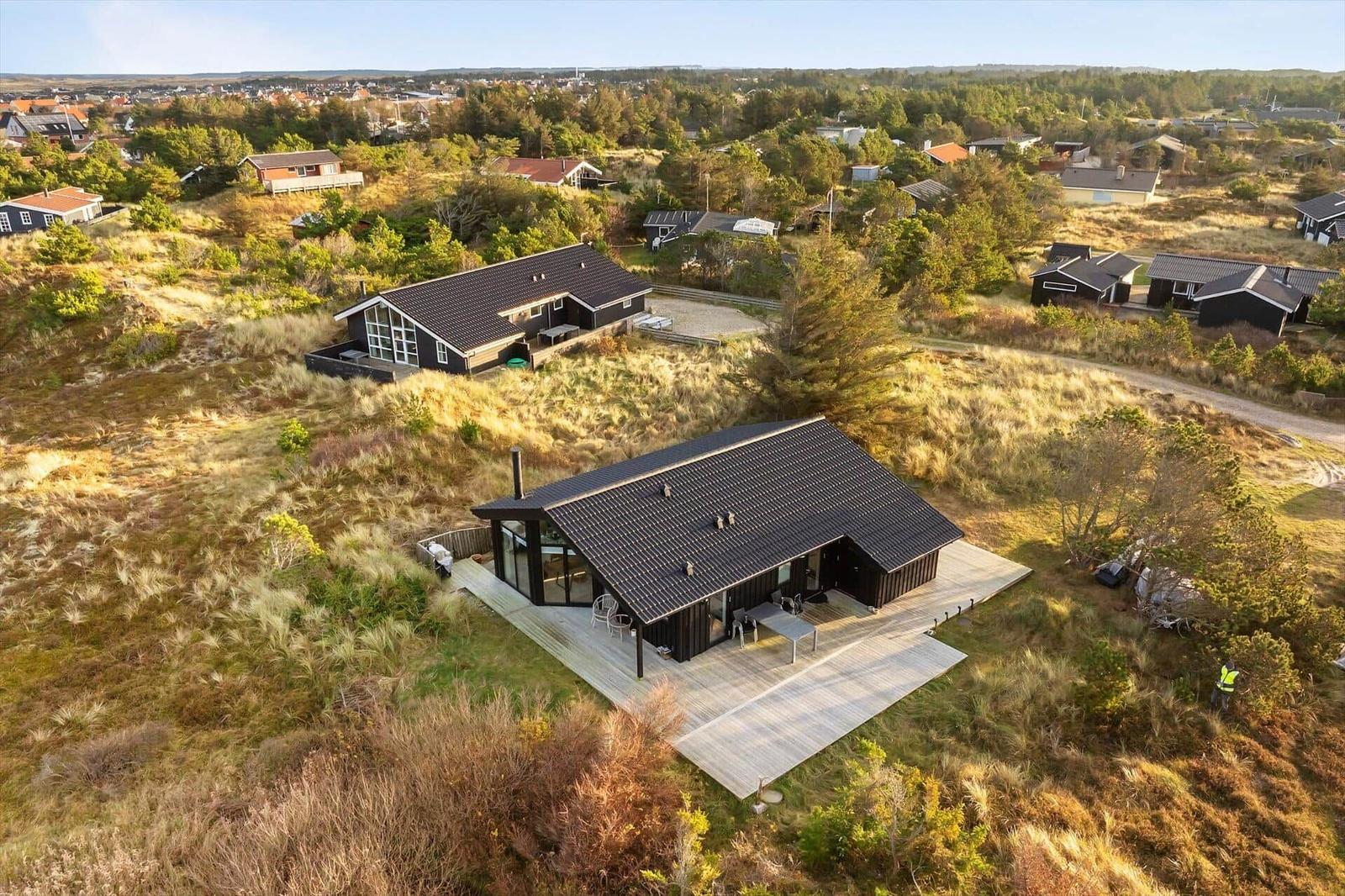 Two modern houses on dunes with terraces and view of the landscape.