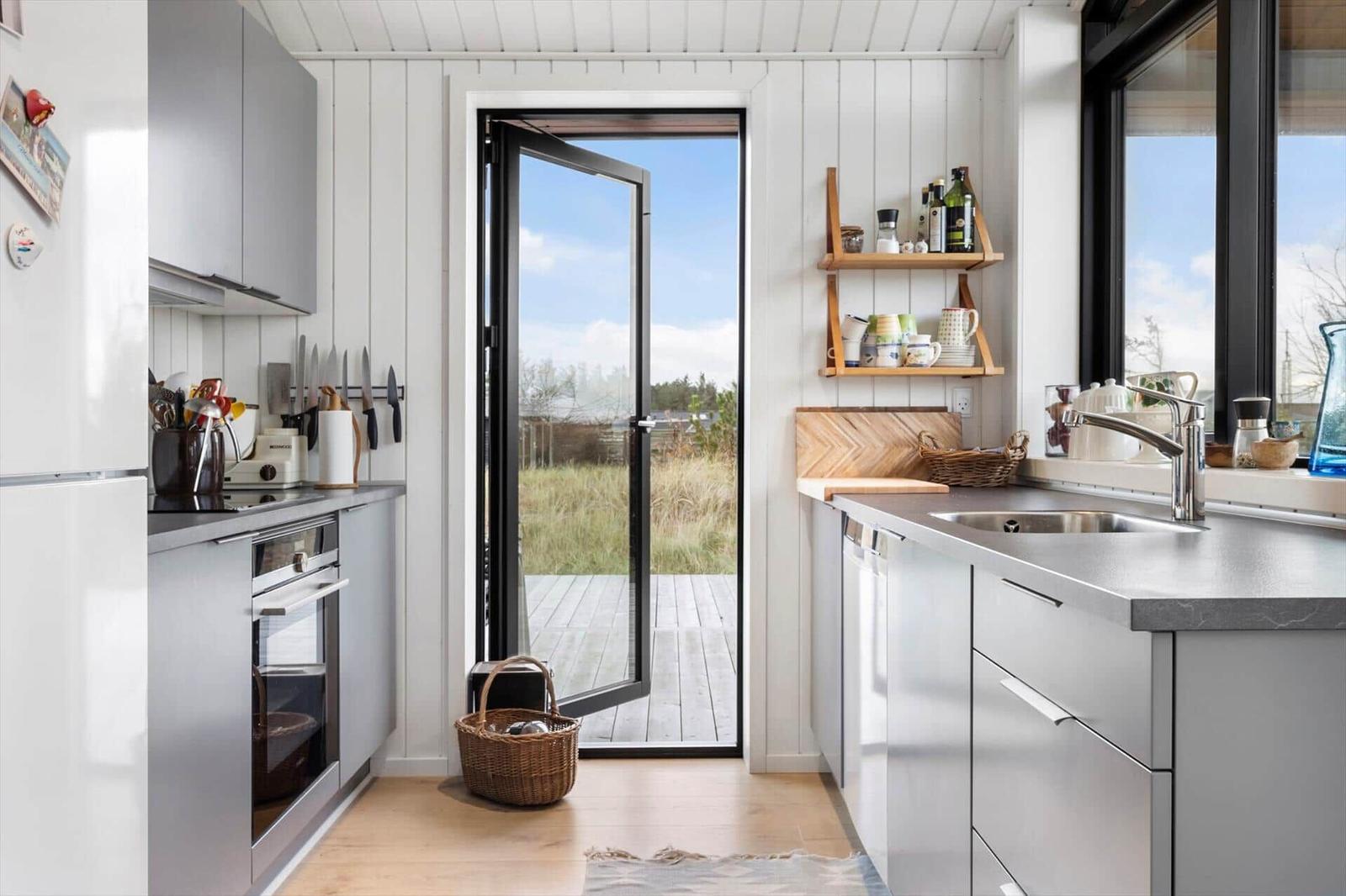 Kitchen with view of terrace and garden. Modern appliances and furniture.
