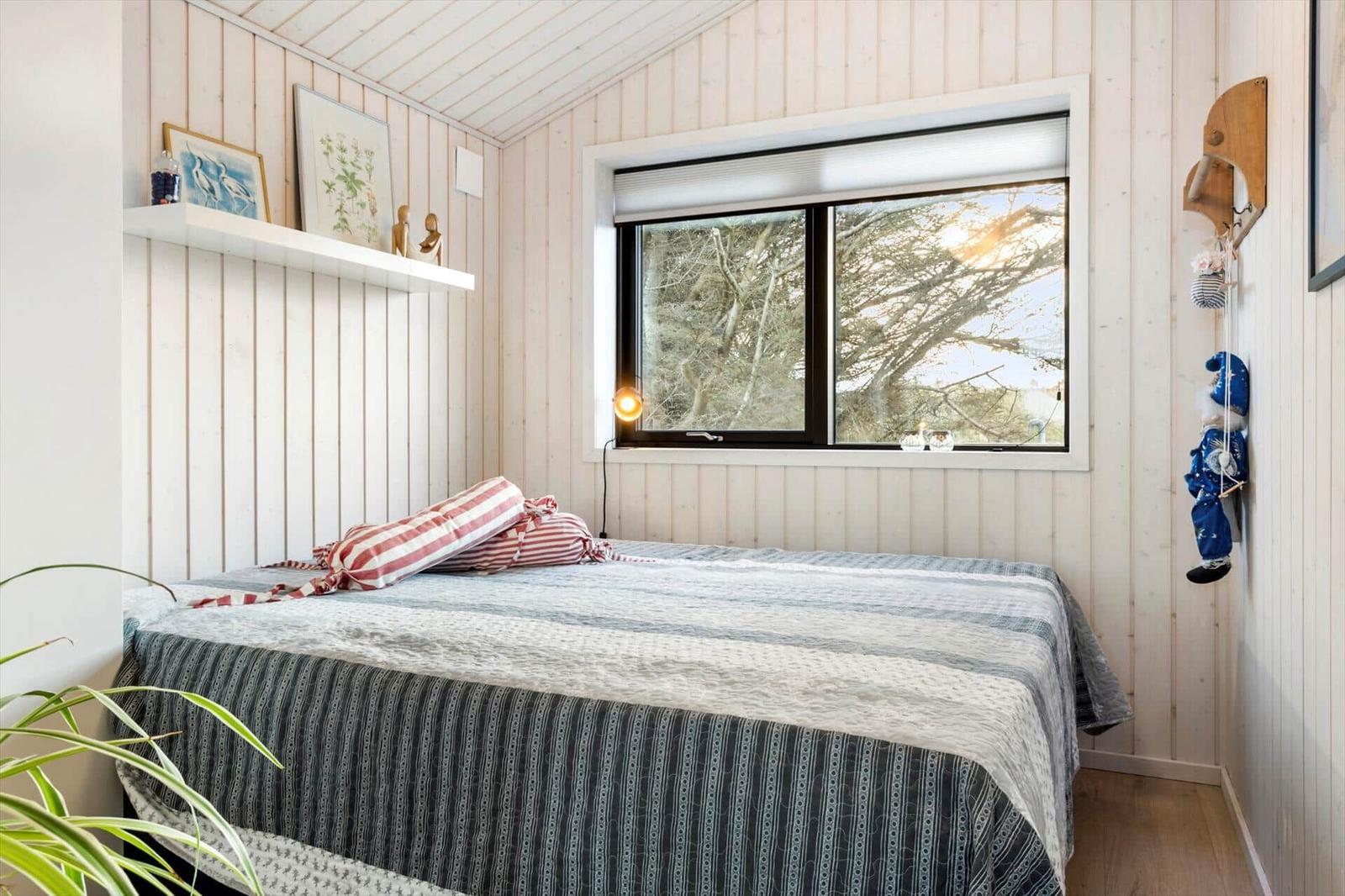 Bedroom with bed, window, and wall shelf.