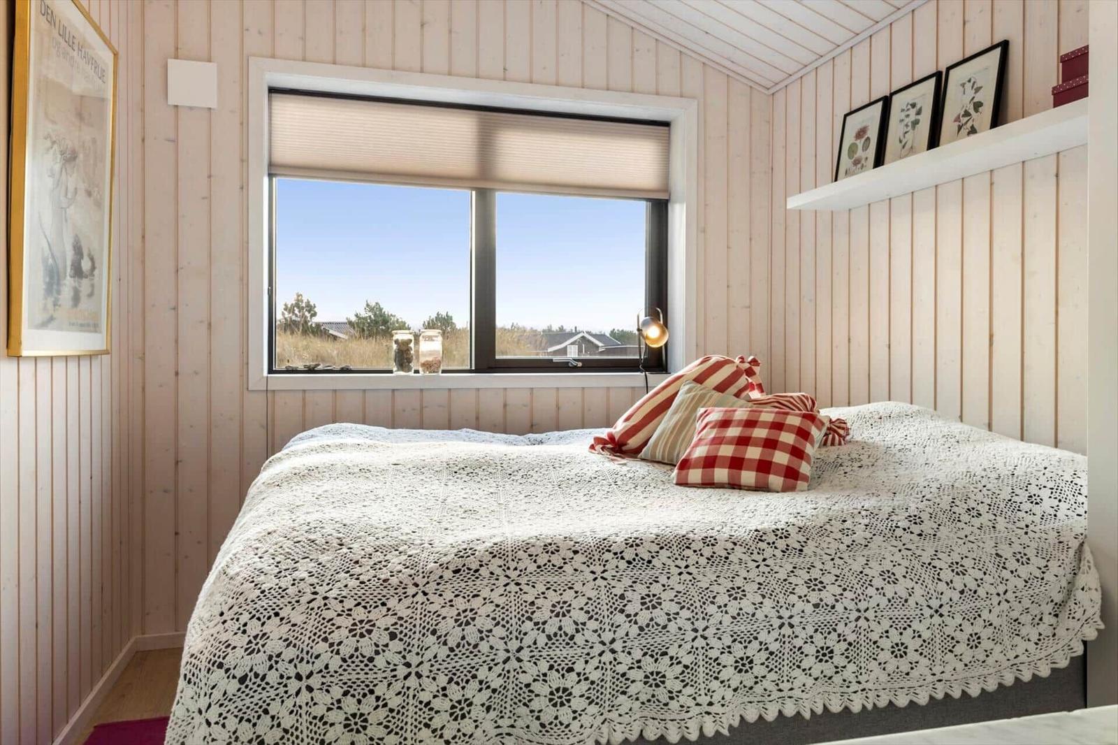 Bedroom with bed, window, and wooden walls.