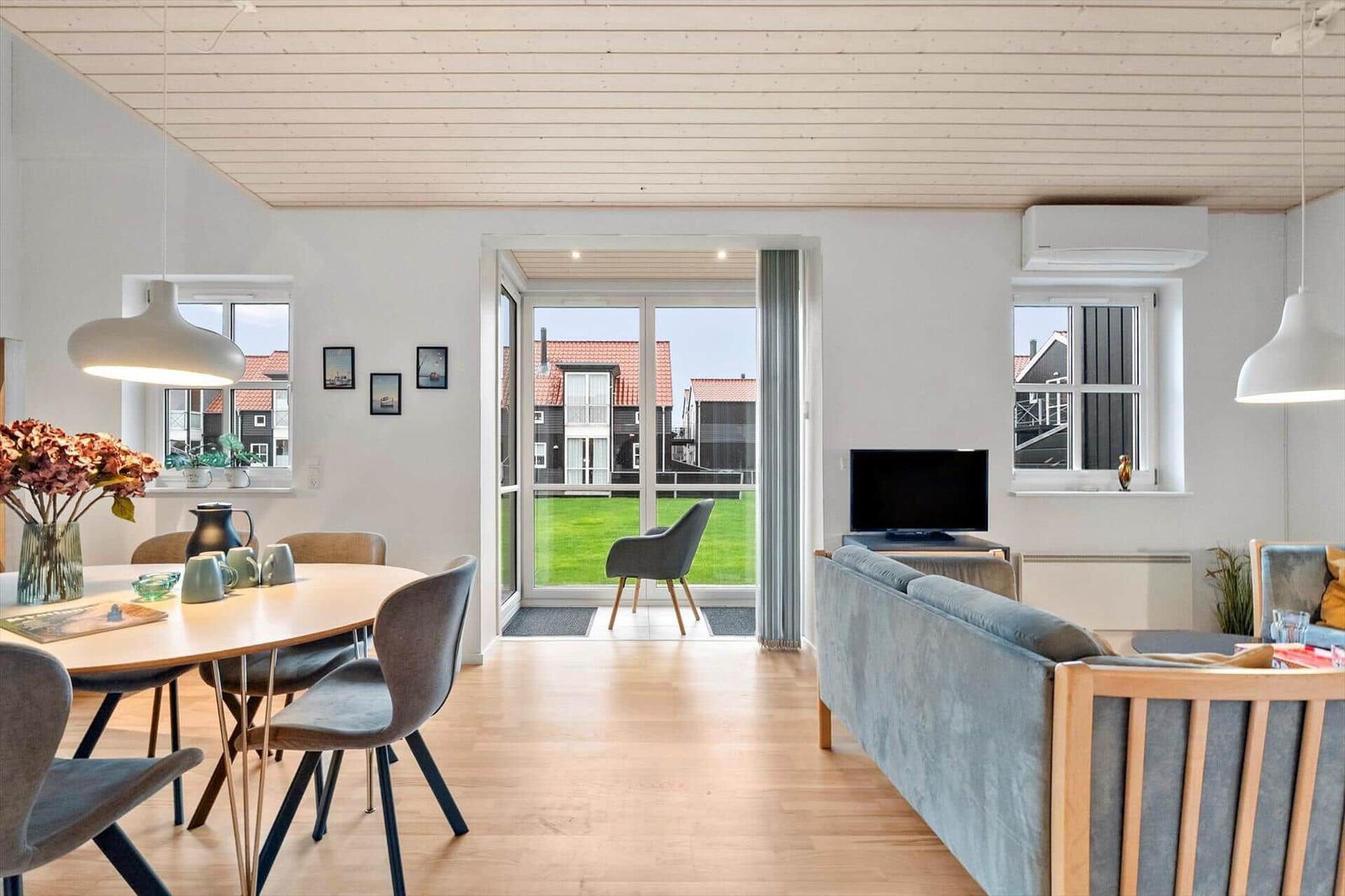 Living and dining area with view of green garden and neighboring houses.