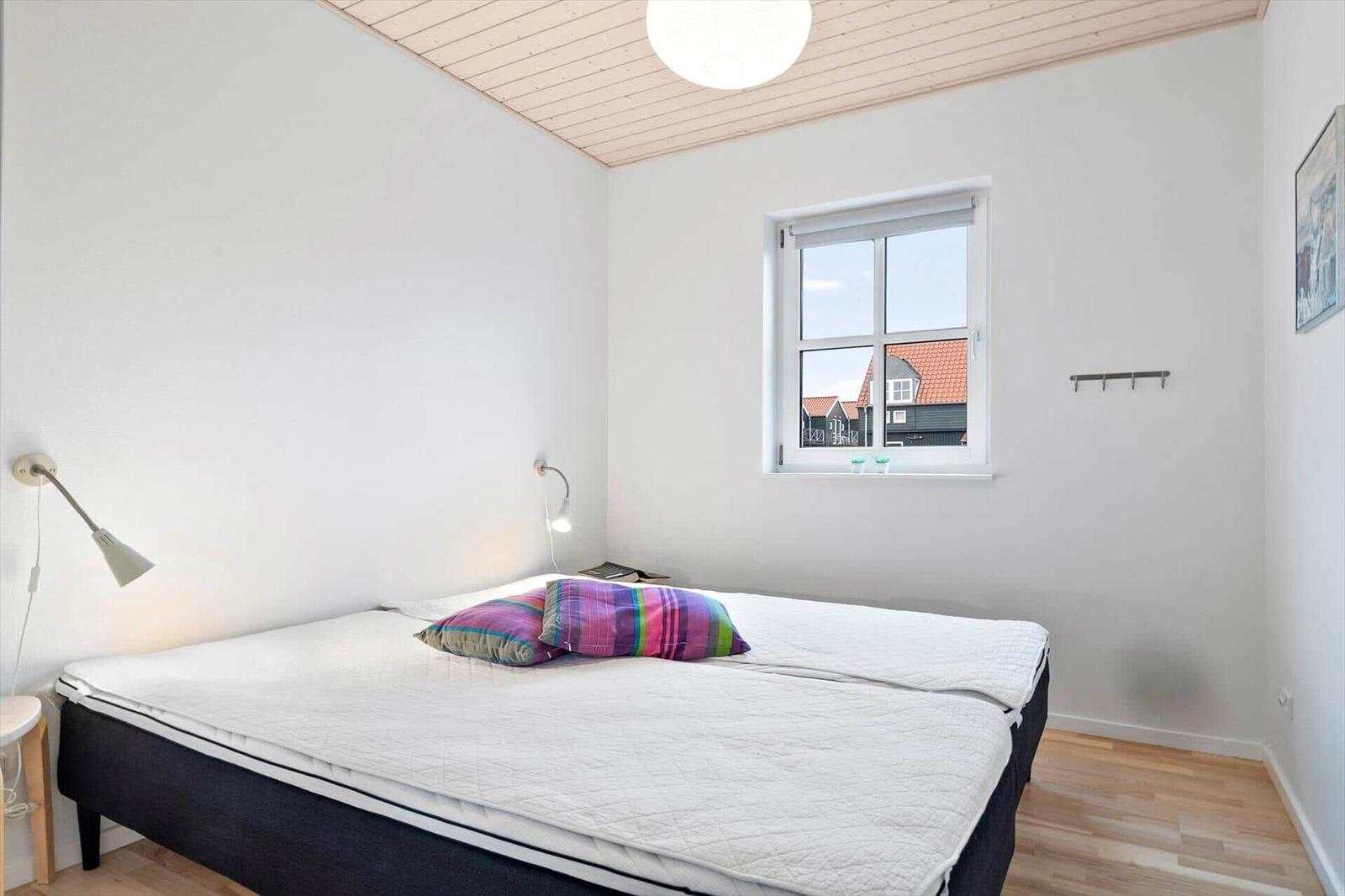 Bedroom with bed, window, and wooden floor.