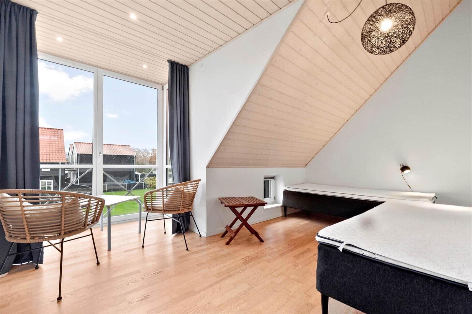 Room with two beds, wooden floor, and large window with outdoor view.