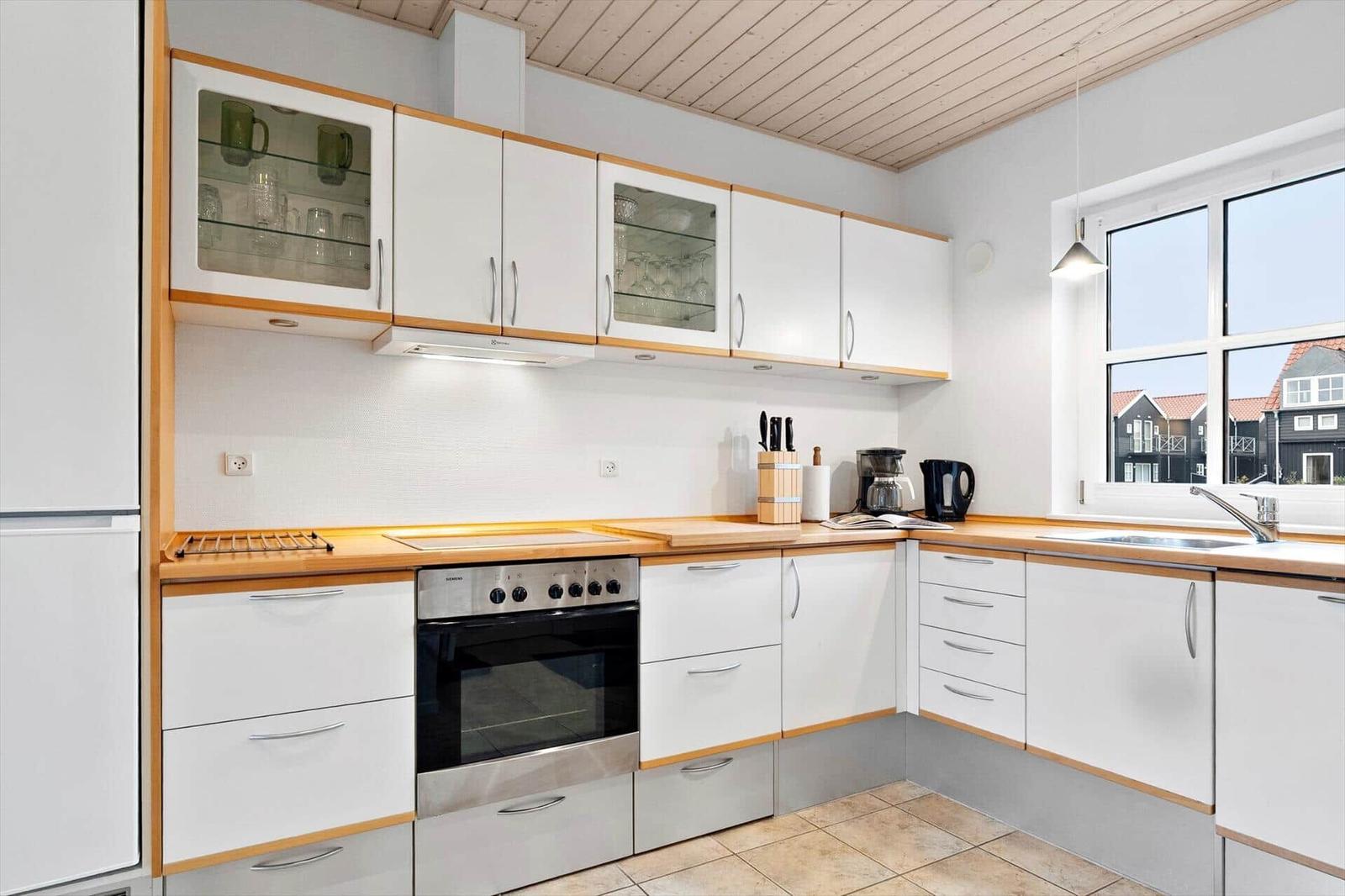 Kitchen with white cabinets, wooden countertops, and window view of houses.