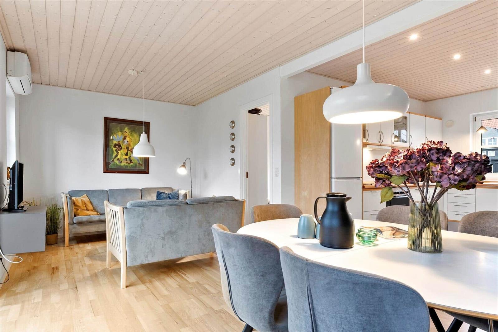 Living and dining area with wooden ceiling, sofa, and dining table with chairs.