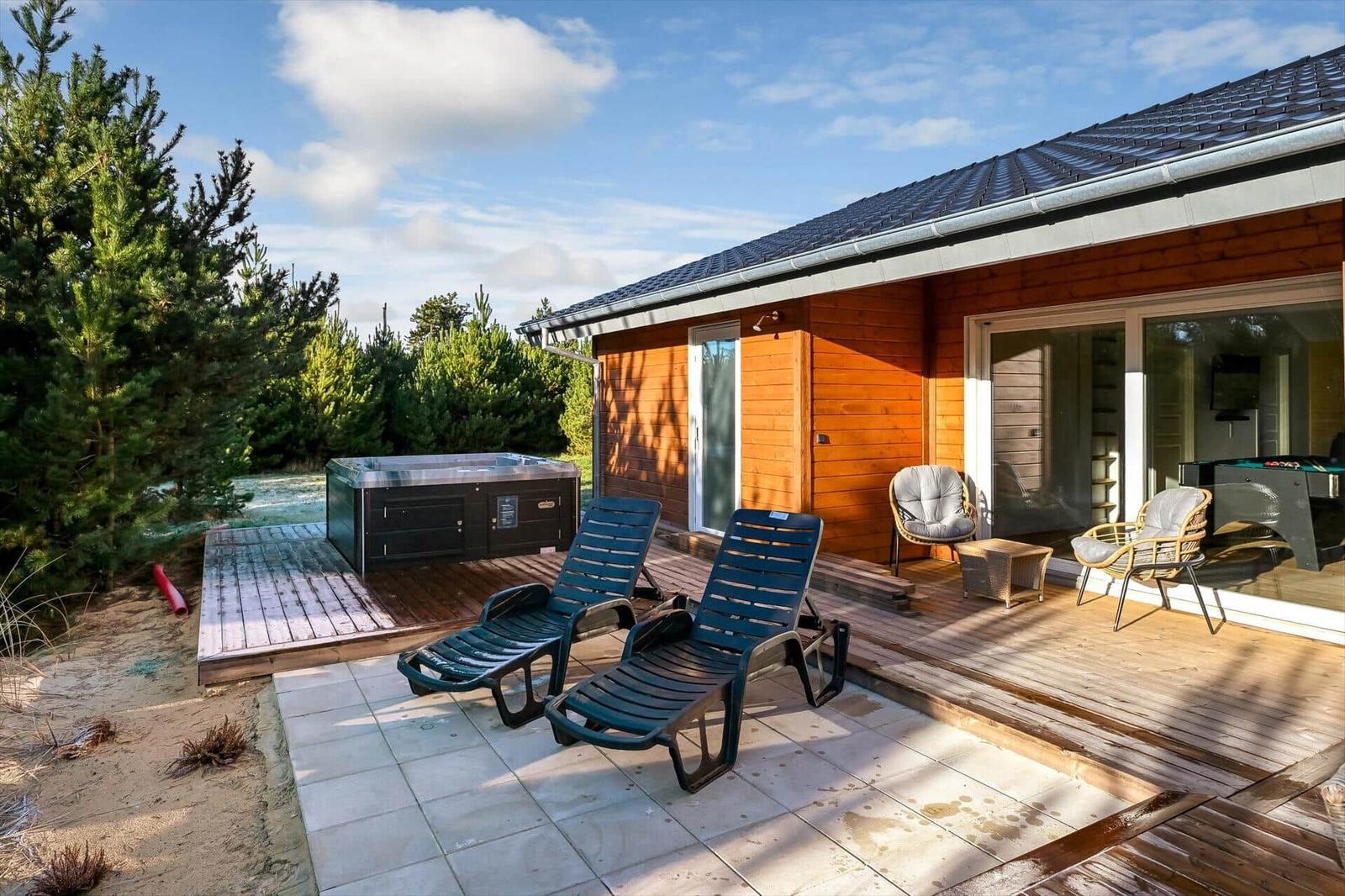 Deck with loungers, hot tub, and view of forest.