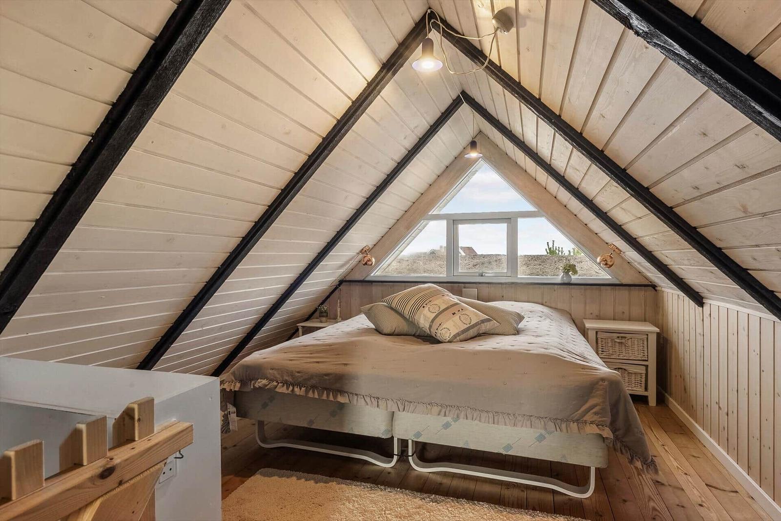 Schlafzimmer mit Dachschrägen, Bett und Fenster