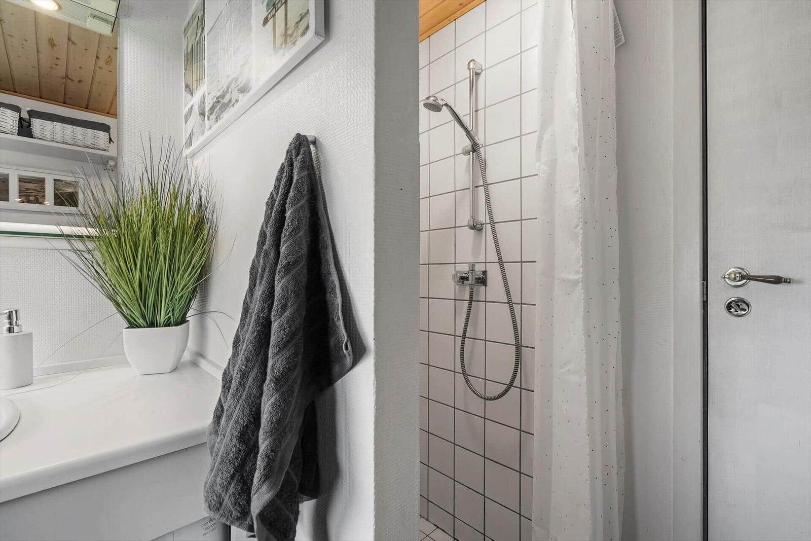 Bad mit Dusche, Waschbecken und Handtuchhalter.
