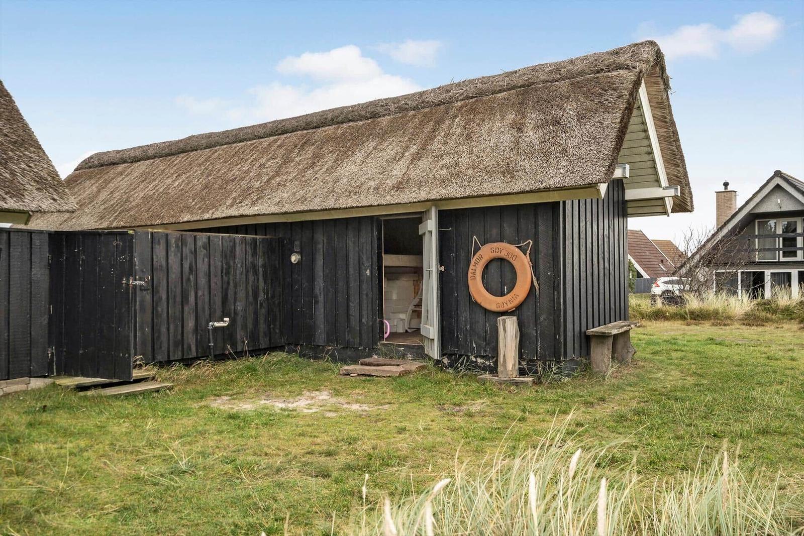 Holzhaus mit Strohdach und Rettungsring an der Tür.
