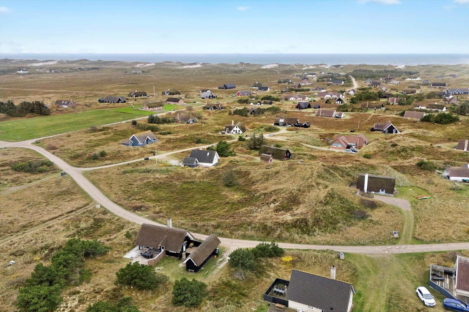 Dorf mit Häusern auf Dünen, Blick auf das Meer.