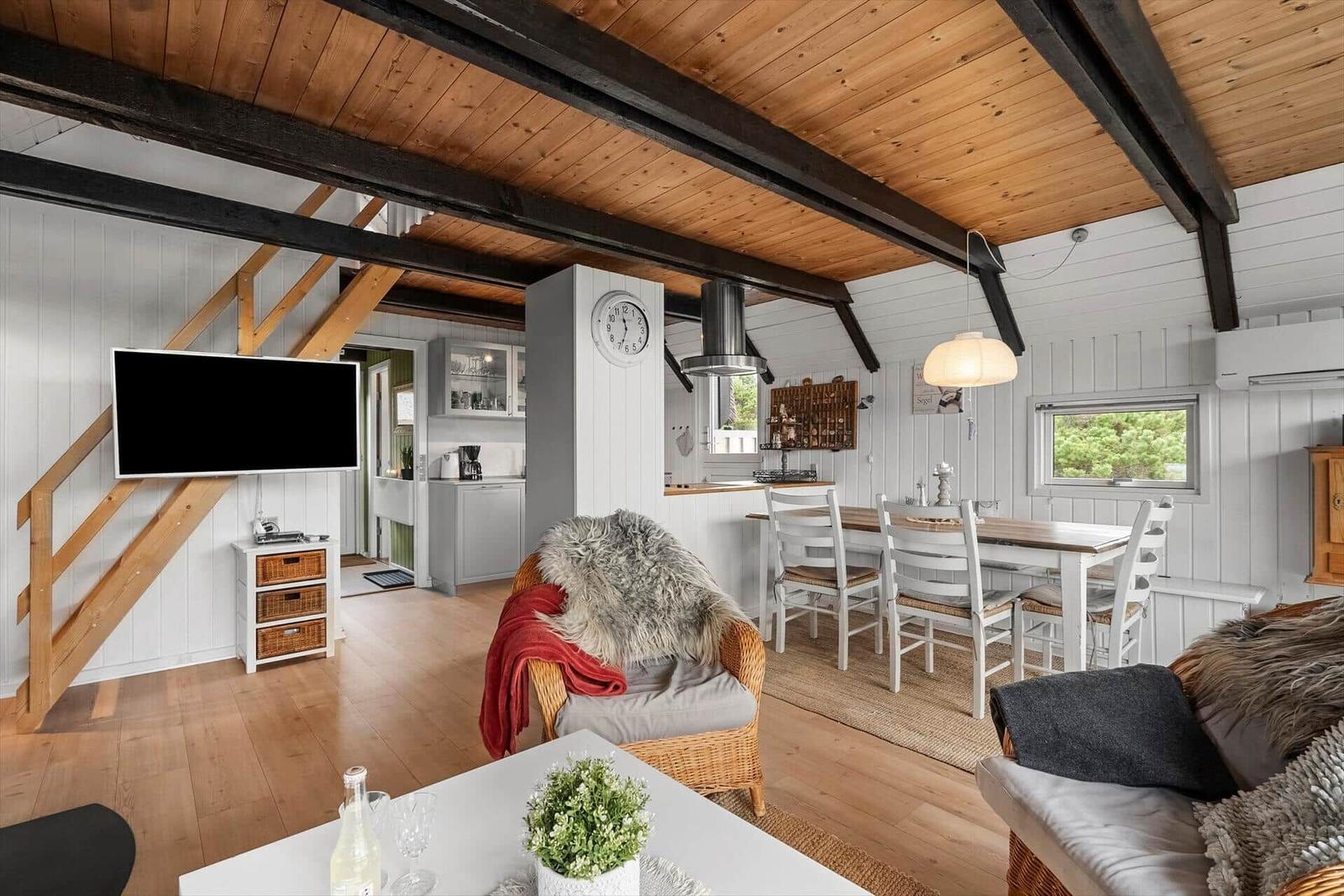 Wohn- und Essbereich mit Holzdecke, TV und Esstisch.