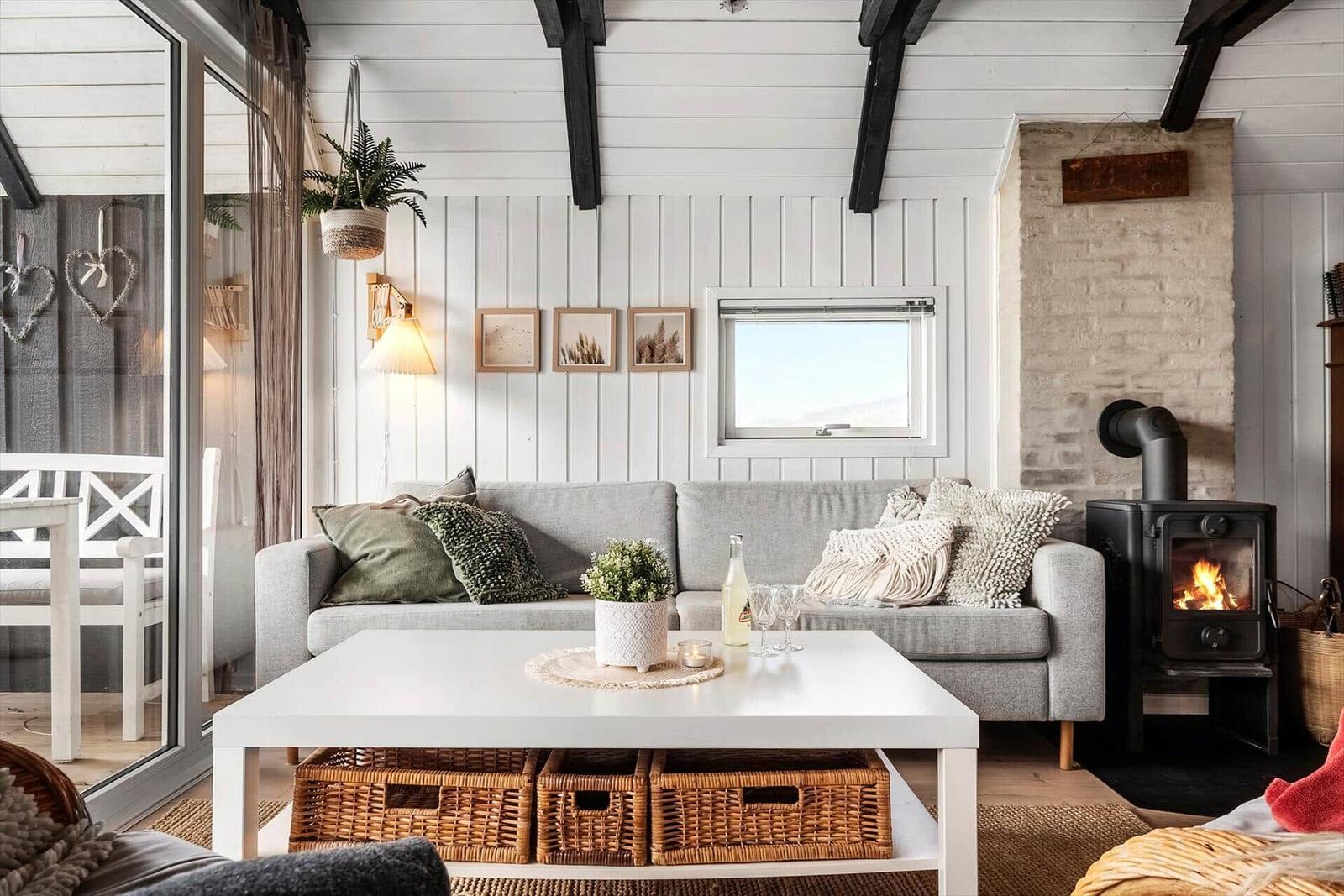 Wohnzimmer mit Sofa, Kamin und Fenster. Tisch mit Körben darunter.