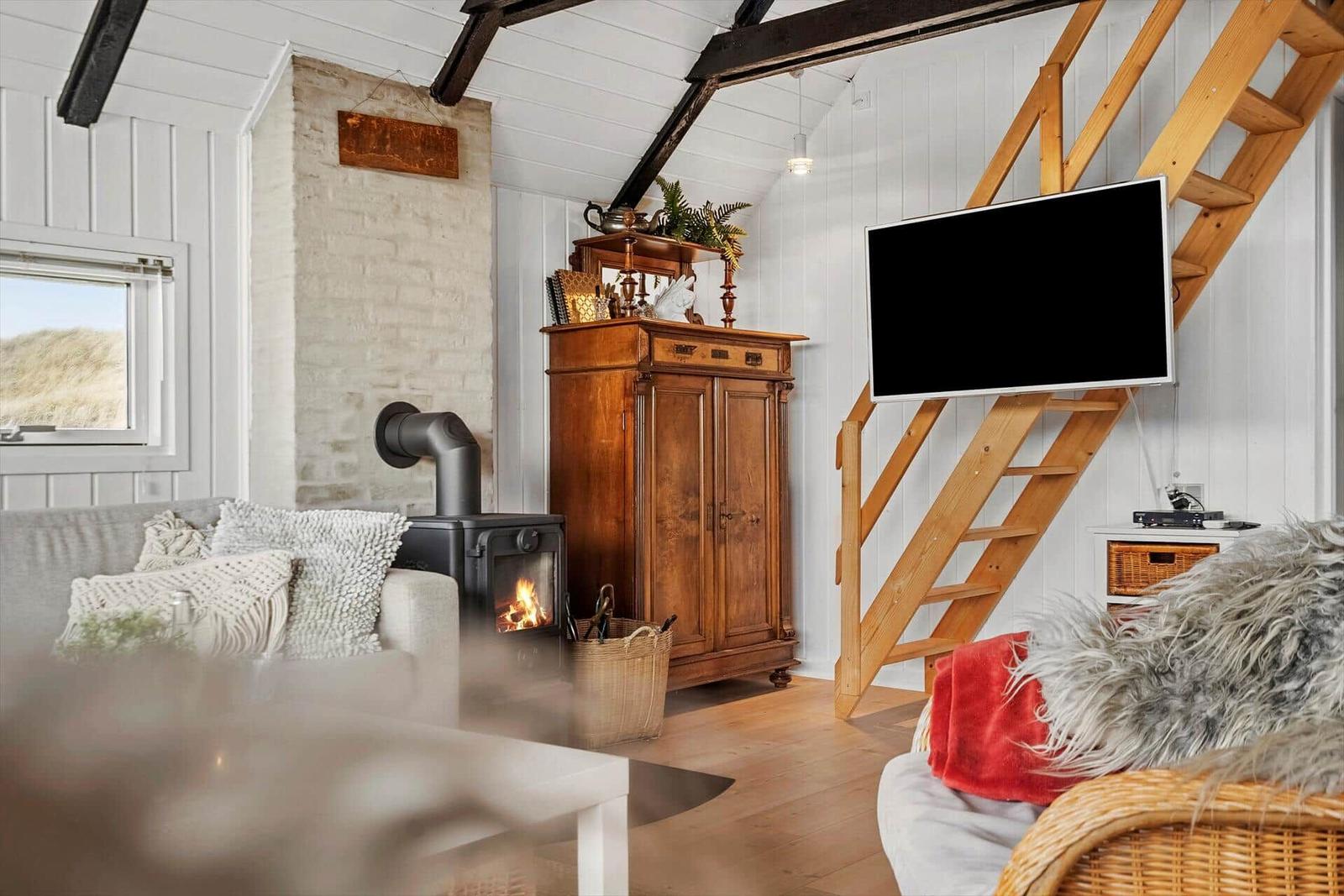Wohnzimmer mit Kamin, Holzstufen und Fernseher an der Wand.