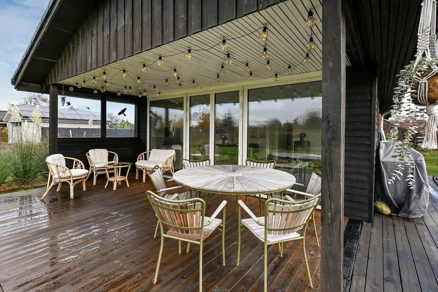Deck with round table and chairs under string lights.