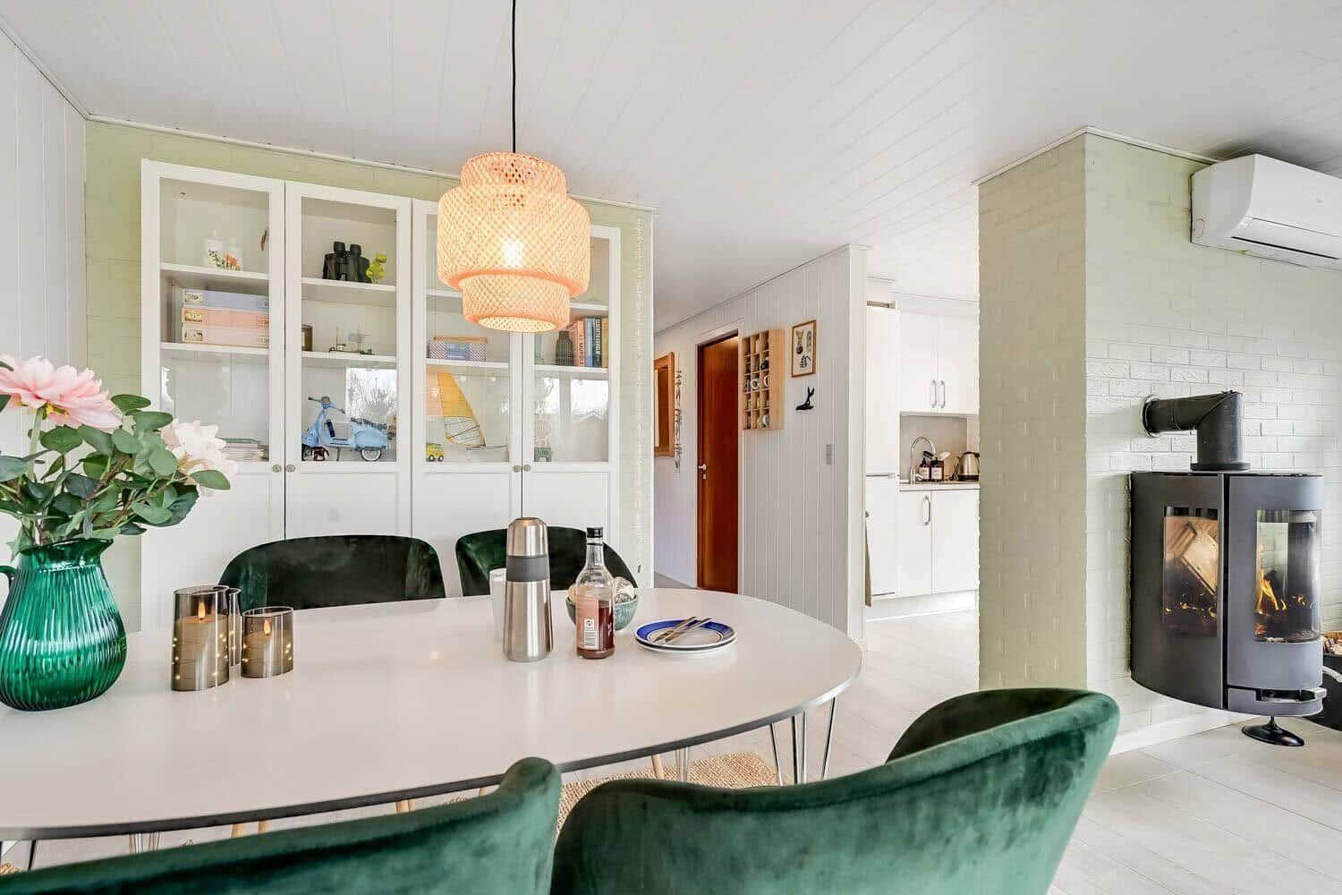 Dining area with round table, green chairs, and wood stove against wall.