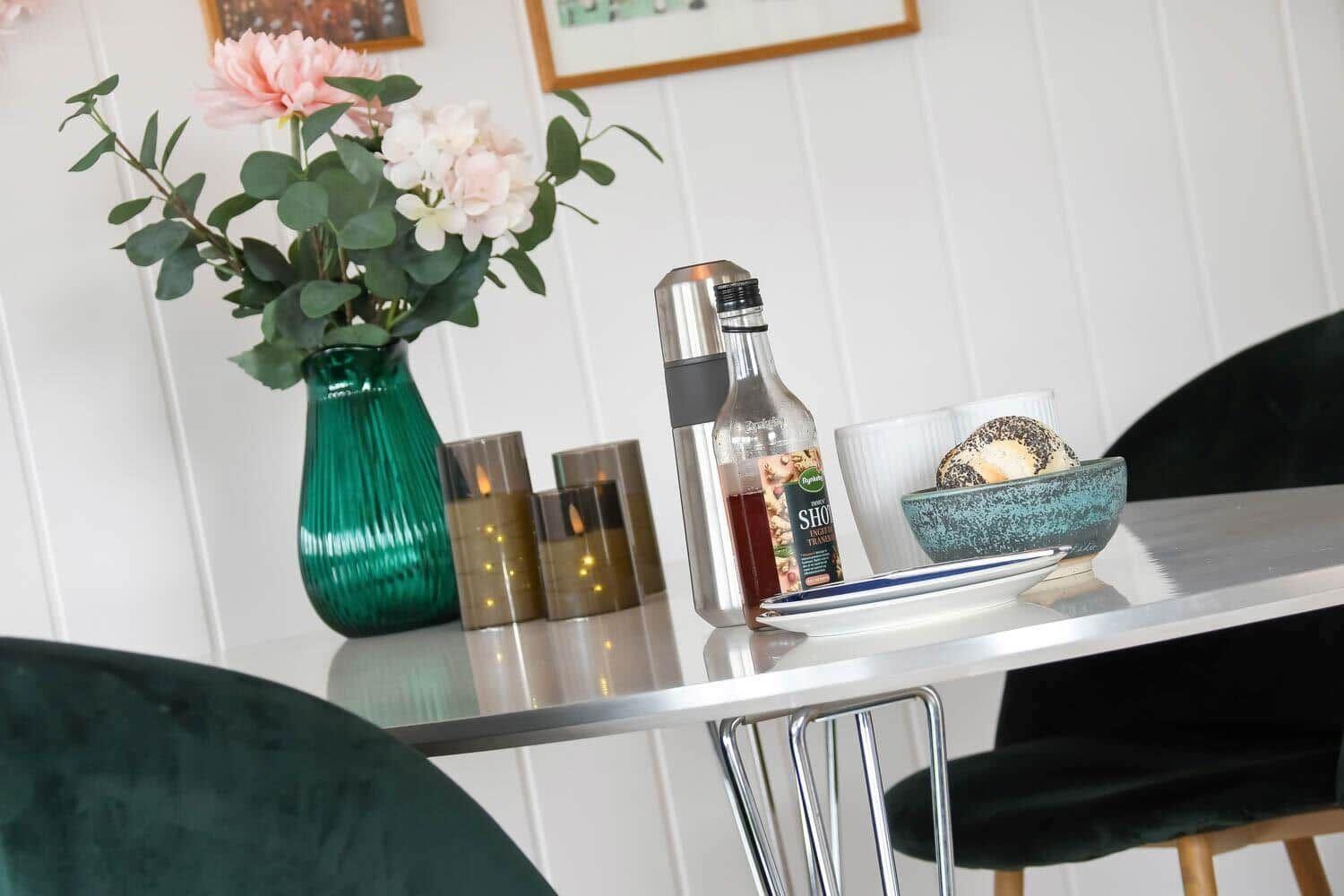 Dining table with green vase, flowers, and drinks