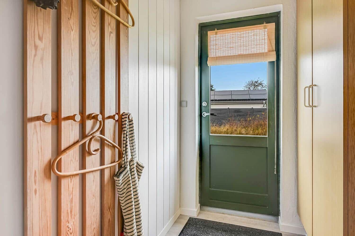 Entrance with green door and wooden coat rack.