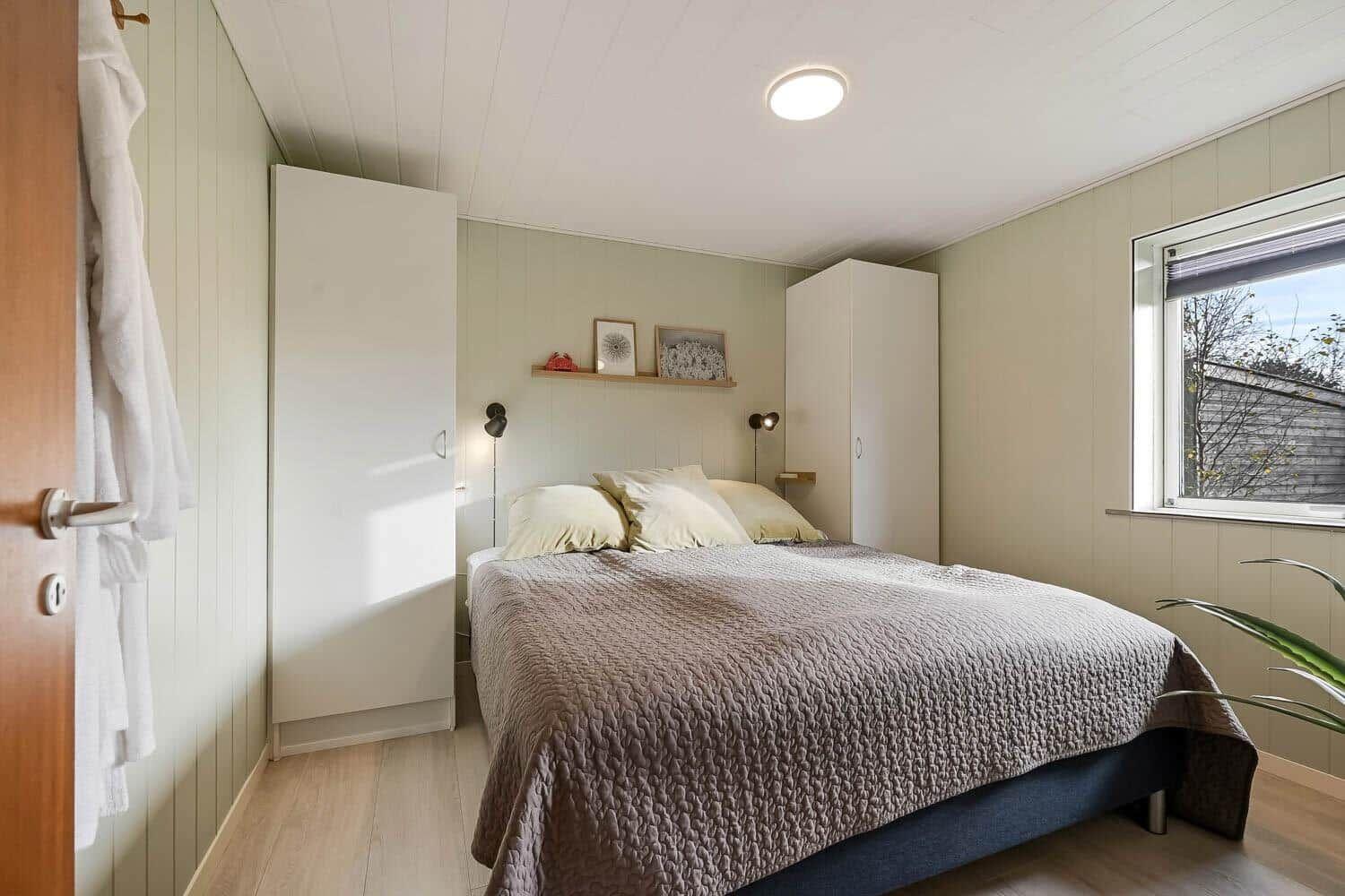 Bedroom with bed, wardrobes, and window.