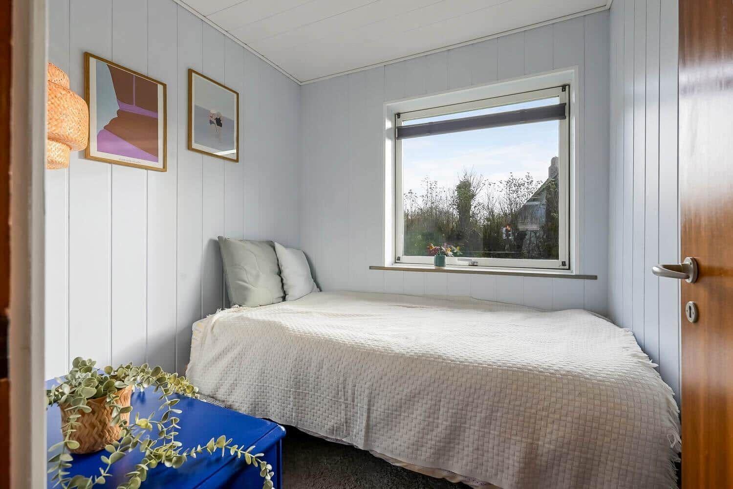 Bedroom with bed, window, and wall pictures.