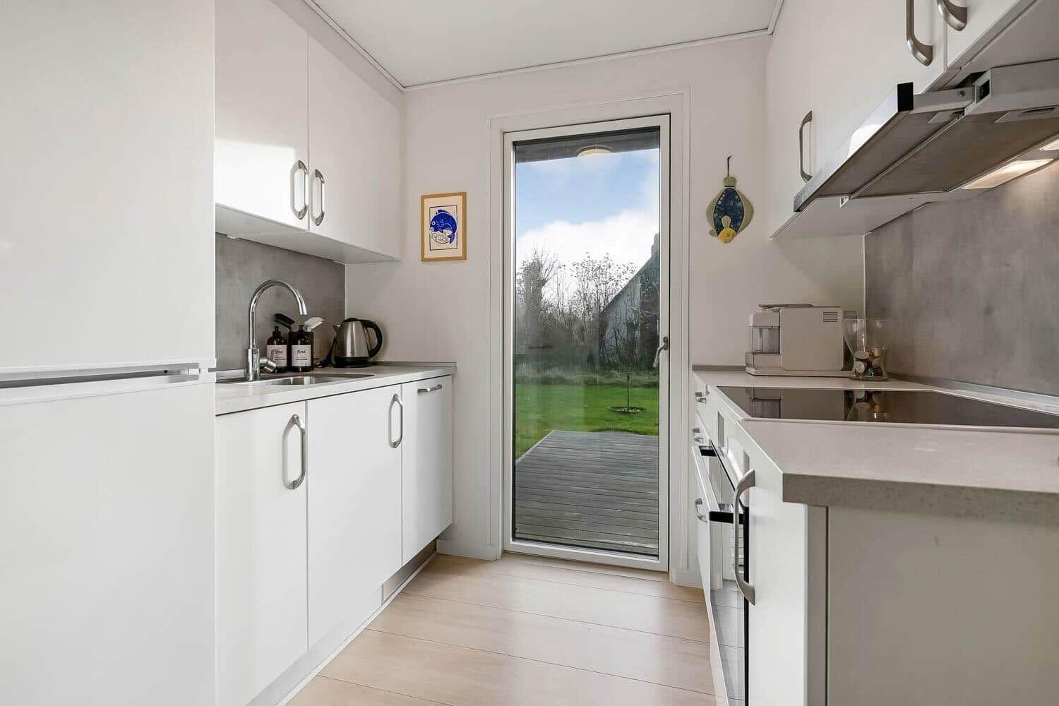 Kitchen with white cabinets, glass door to garden, and modern worktop.