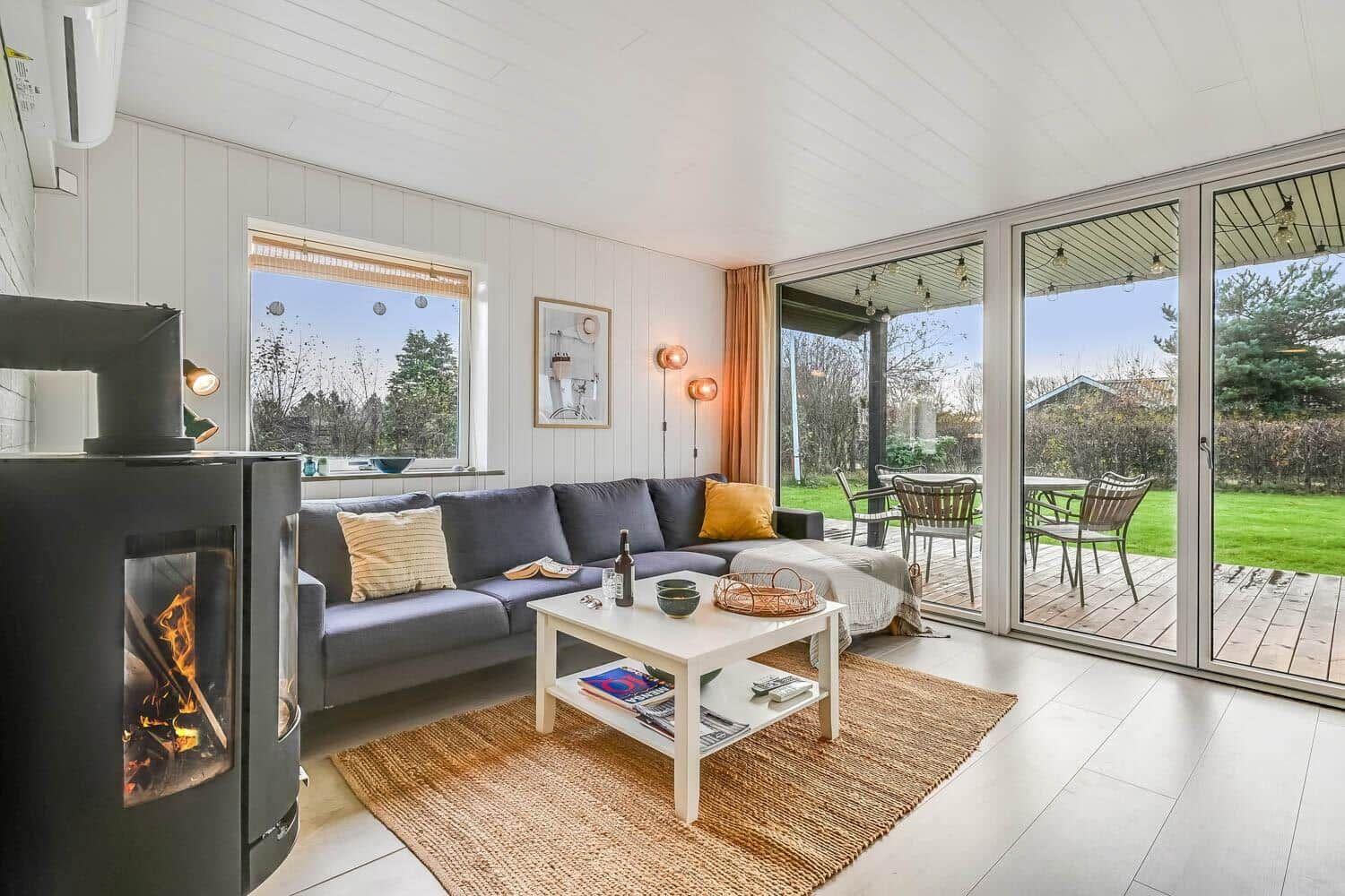 Living room with sofa, fireplace, and terrace with garden view.