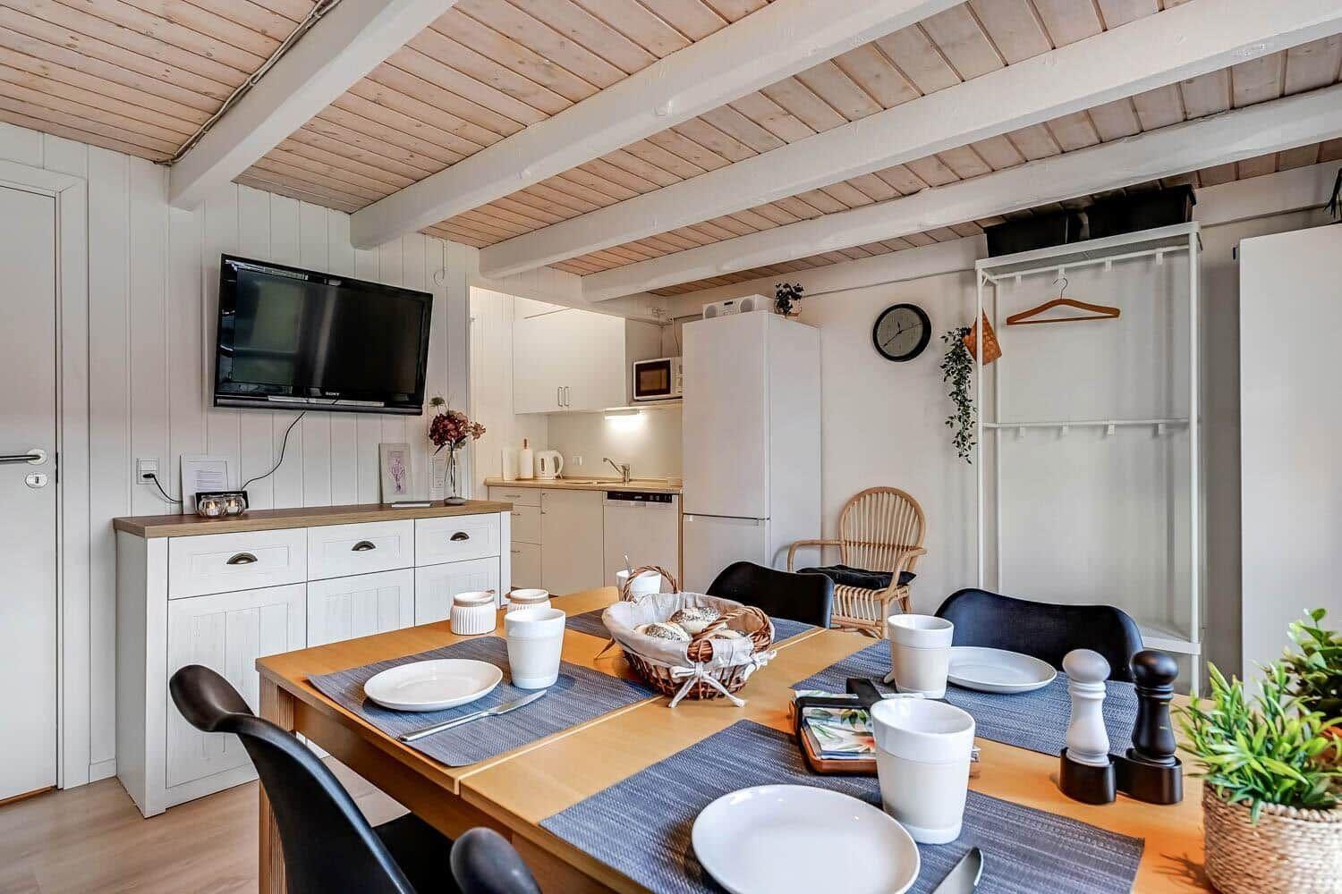 Dining area with table, chairs, and kitchen area in background.