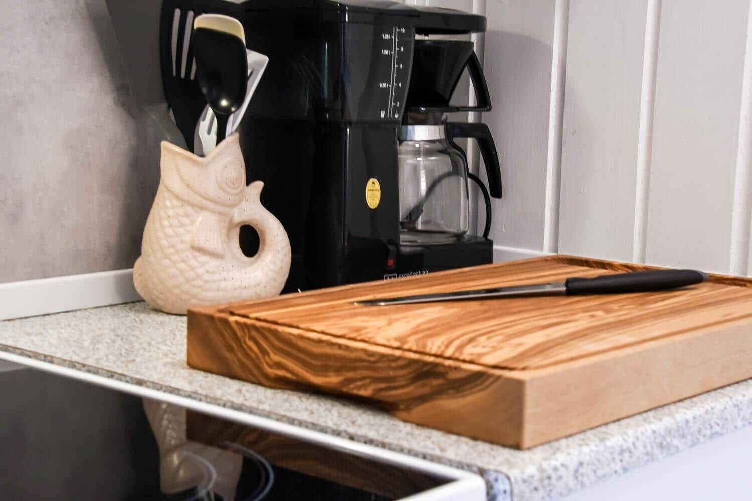 Kitchen counter with cutting board, knife, and coffee maker.