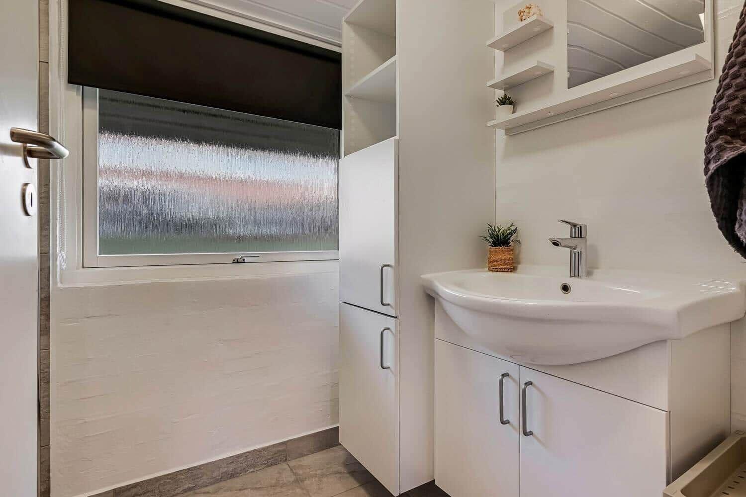 Bathroom with sink, mirror cabinet, and window with textured glass.